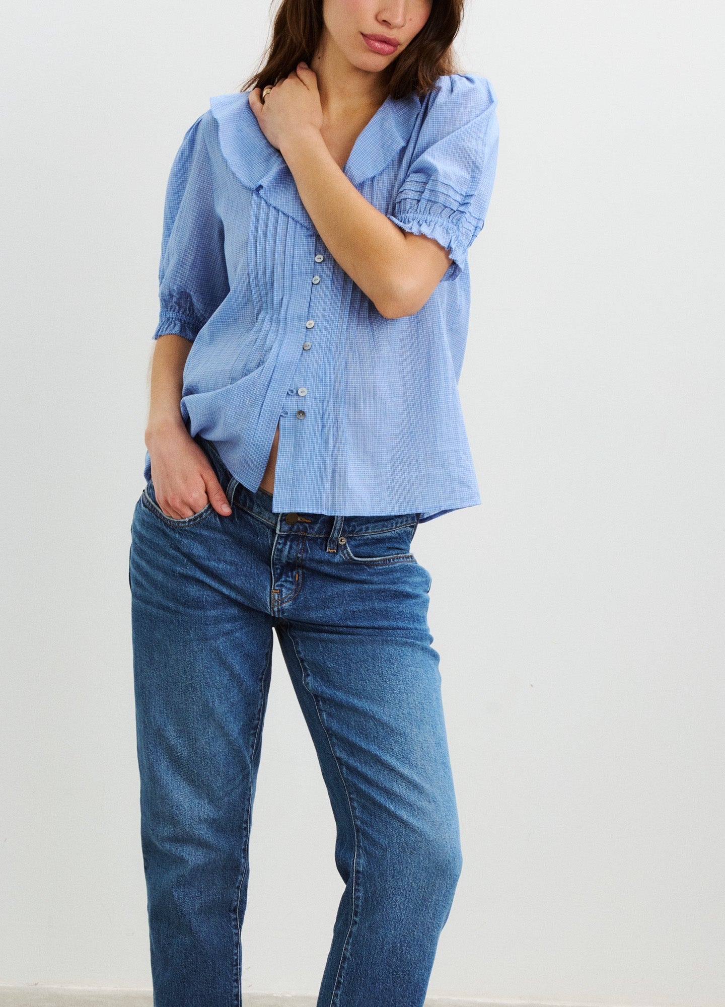 Light blue plaid nursing blouse with puff sleeves and front buttons paired with dark blue jeans.