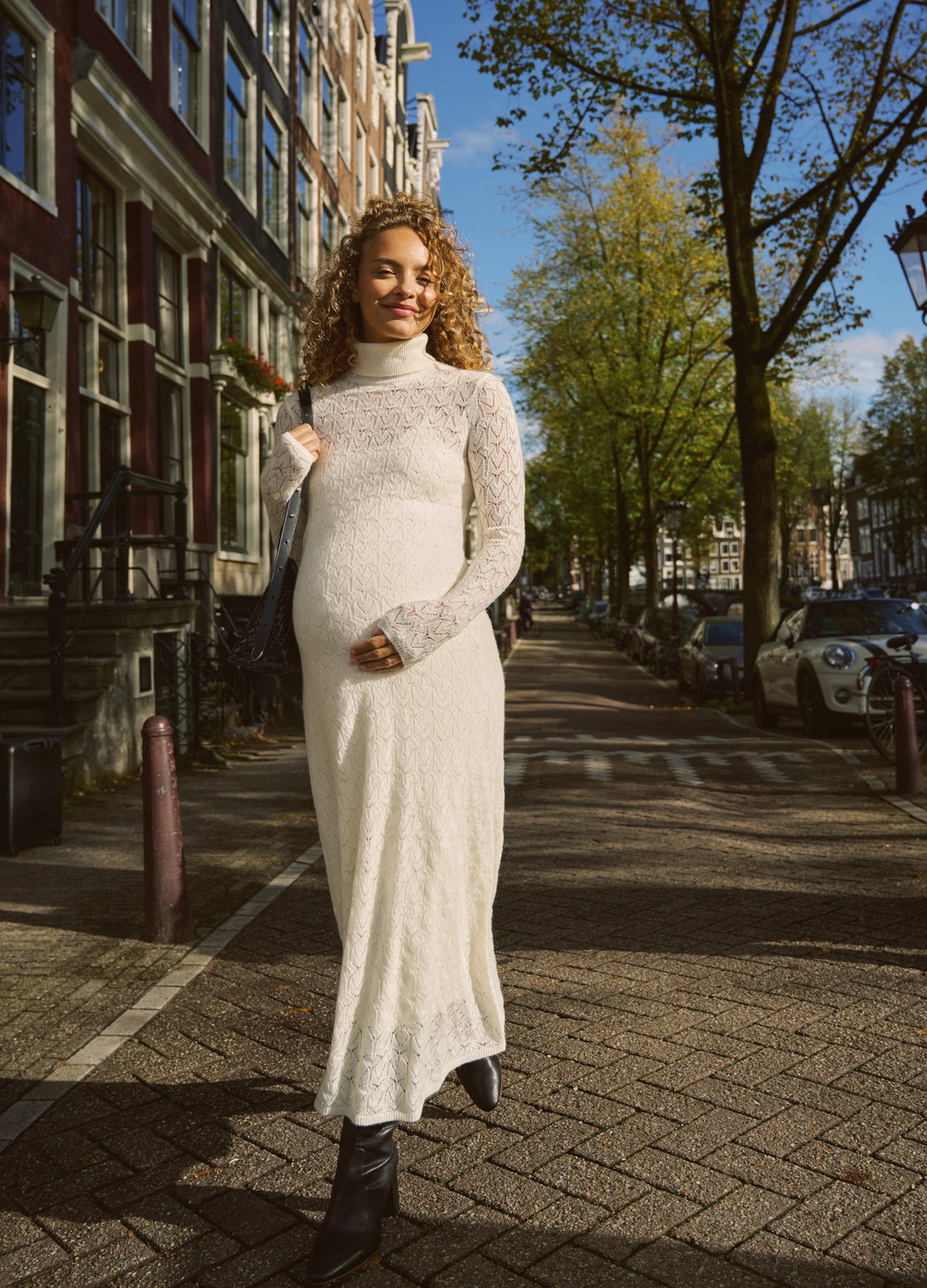 Cream pointelle knit dress with a fitted long-sleeve bodice, high neckline, and flowing ankle-length skirt.