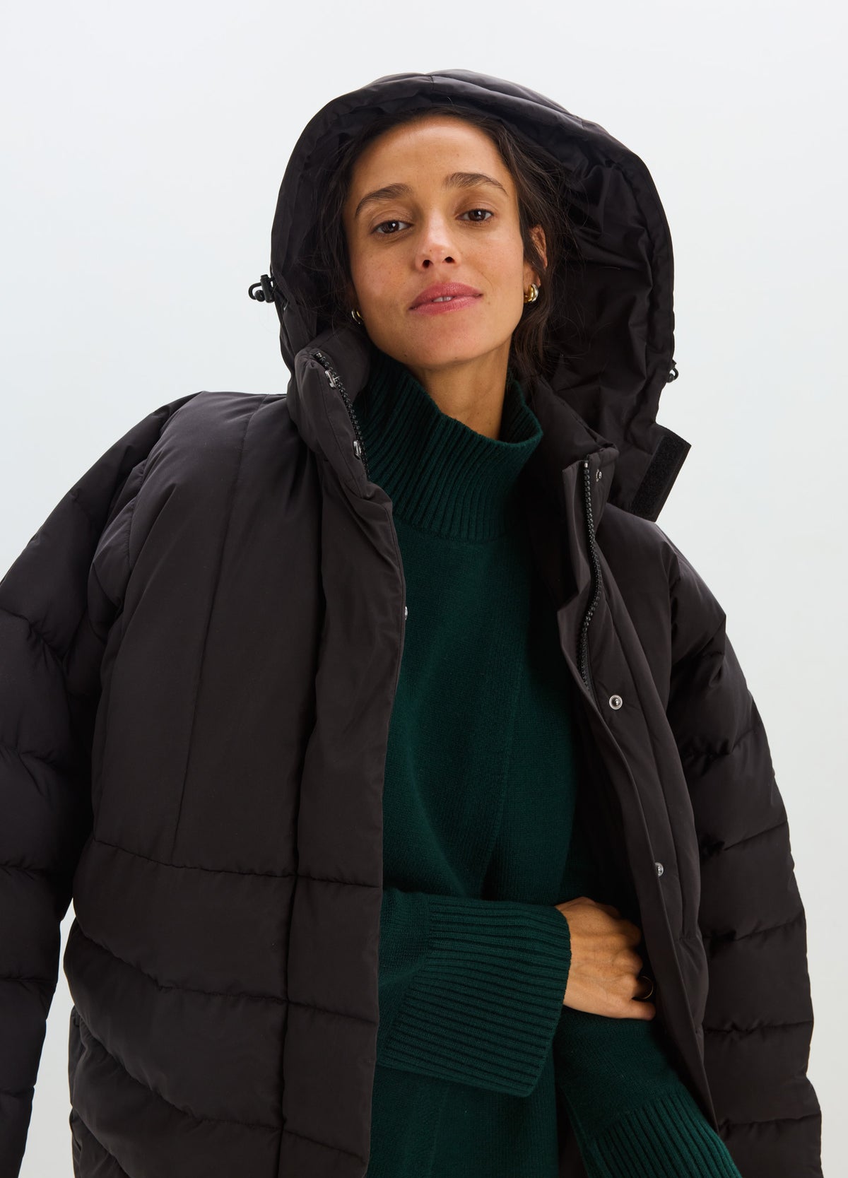 Black quilted puffer jacket with a hood, snap-front closure, and relaxed fit.