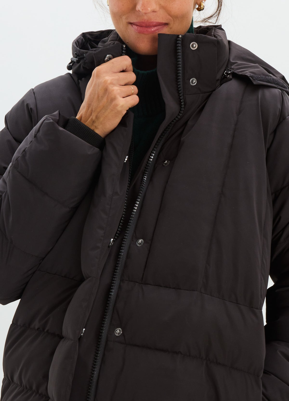 Black quilted puffer jacket with a high collar, snap-button front, and oversized hood.