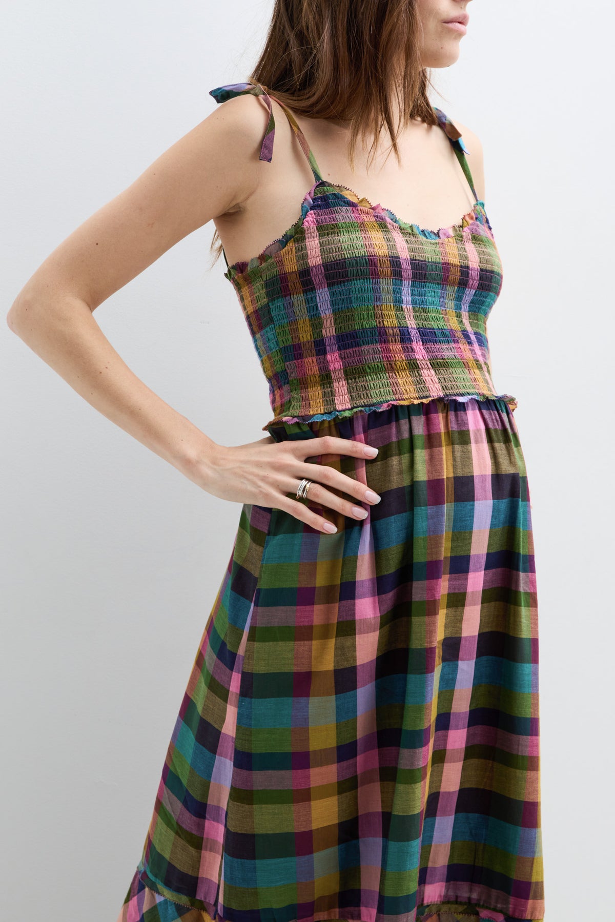 Sleeveless maternity dress with adjustable tie straps, featuring a colorful plaid pattern and gathered waist for comfort.