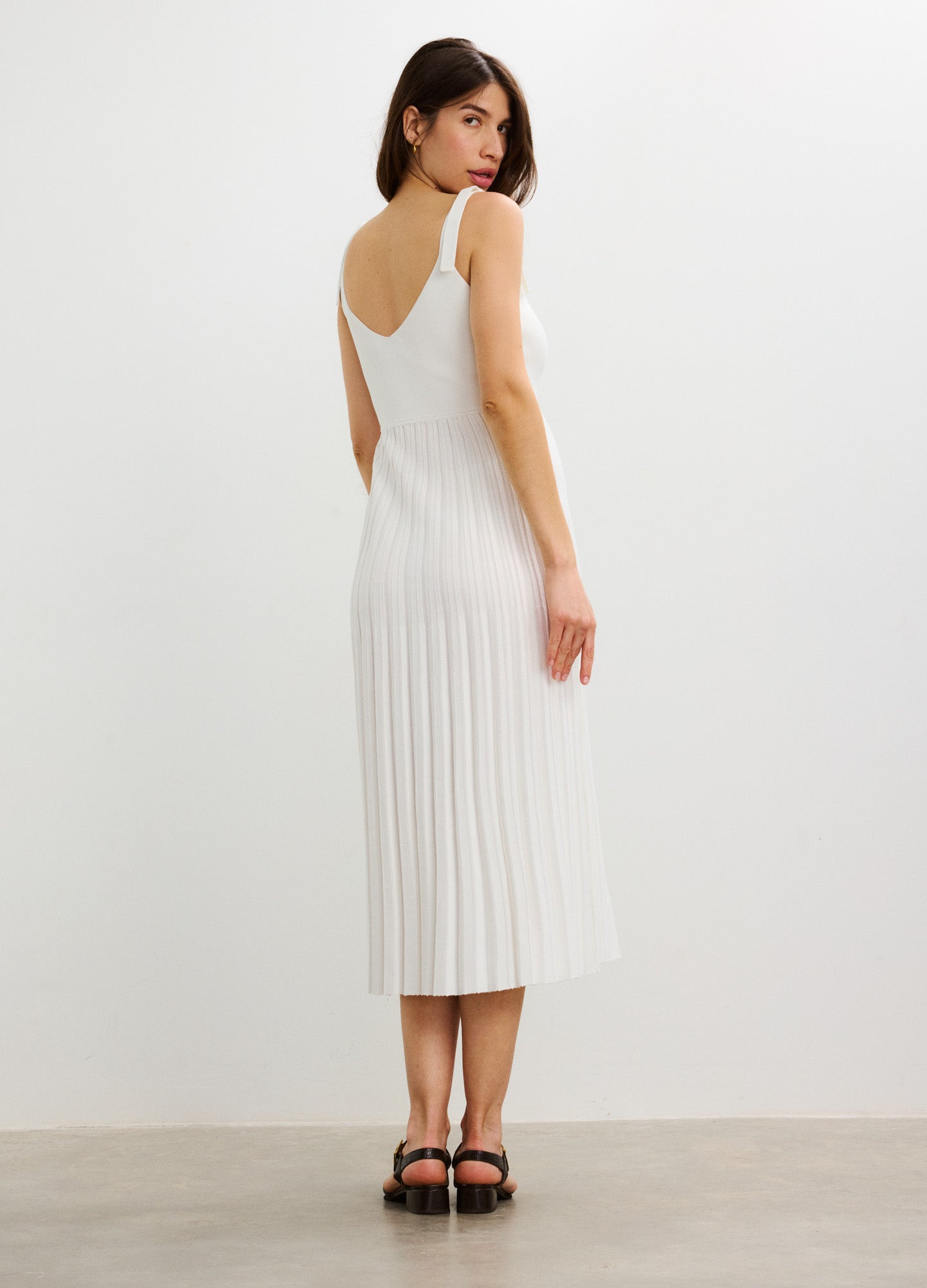 White sleeveless midi dress with vertical rib knit, fitted for maternity wear, featuring a scoop back and soft stretch.