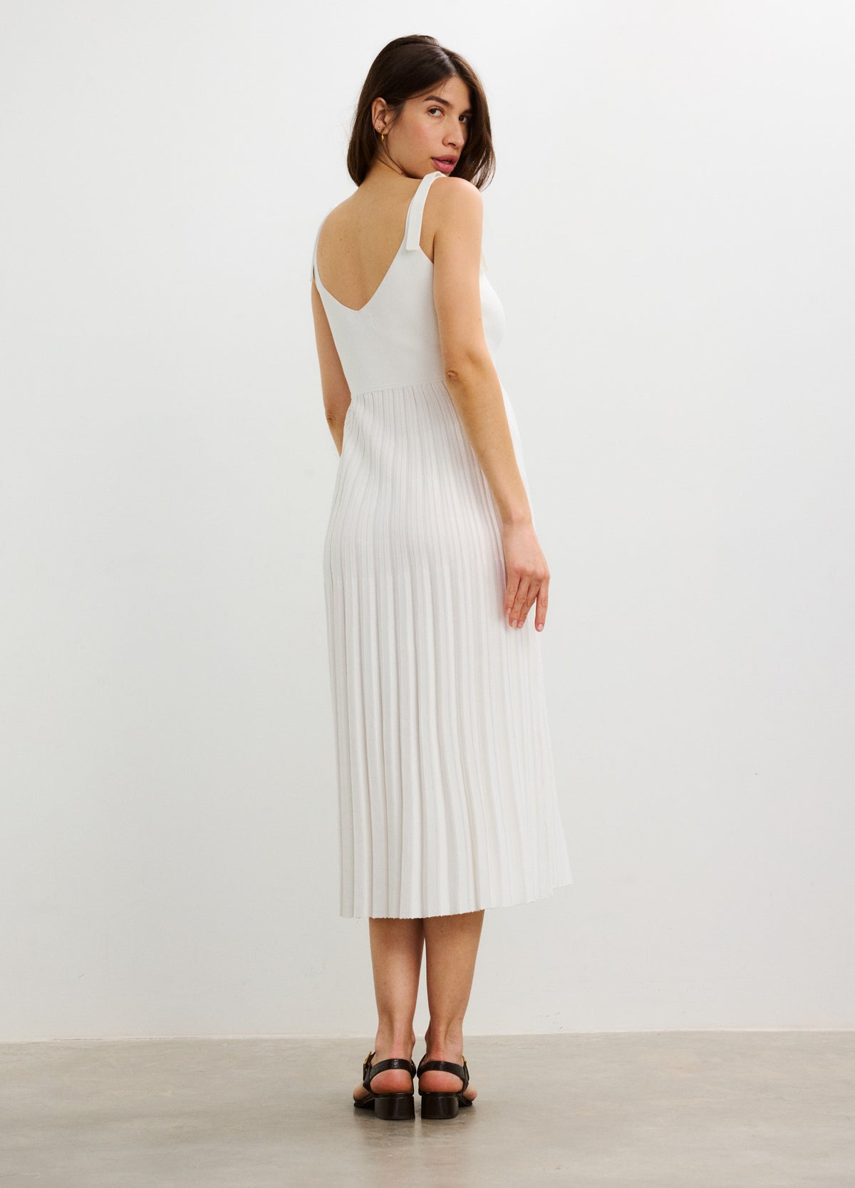 White sleeveless midi dress with vertical rib knit, fitted for maternity wear, featuring a scoop back and soft stretch.
