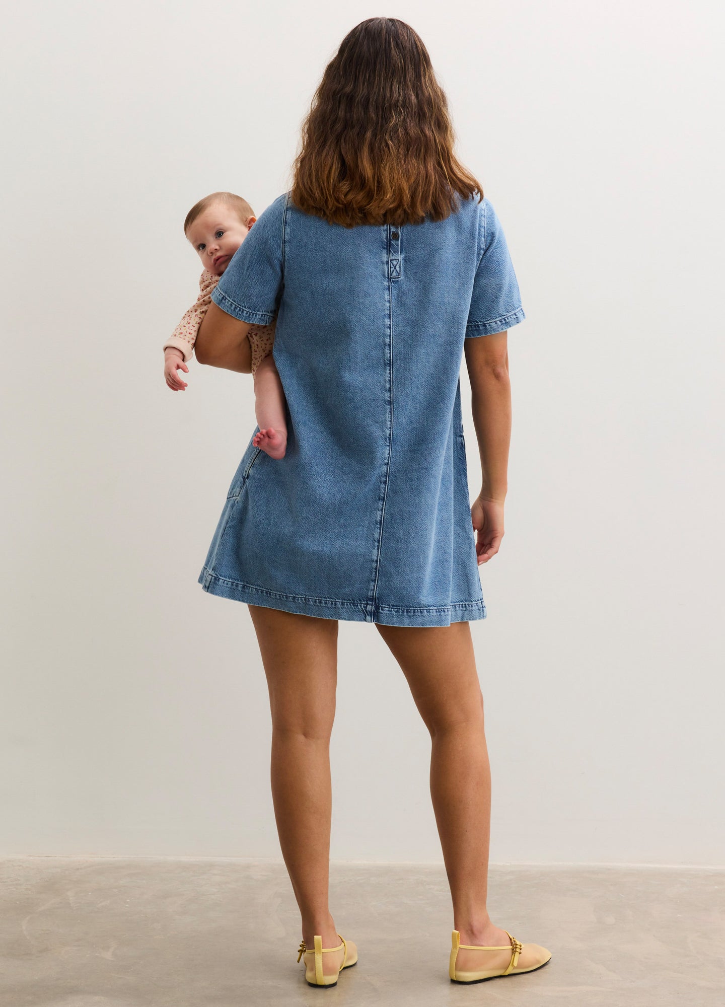 Short-sleeve light blue denim maternity dress with a loose fit and button details down the back.