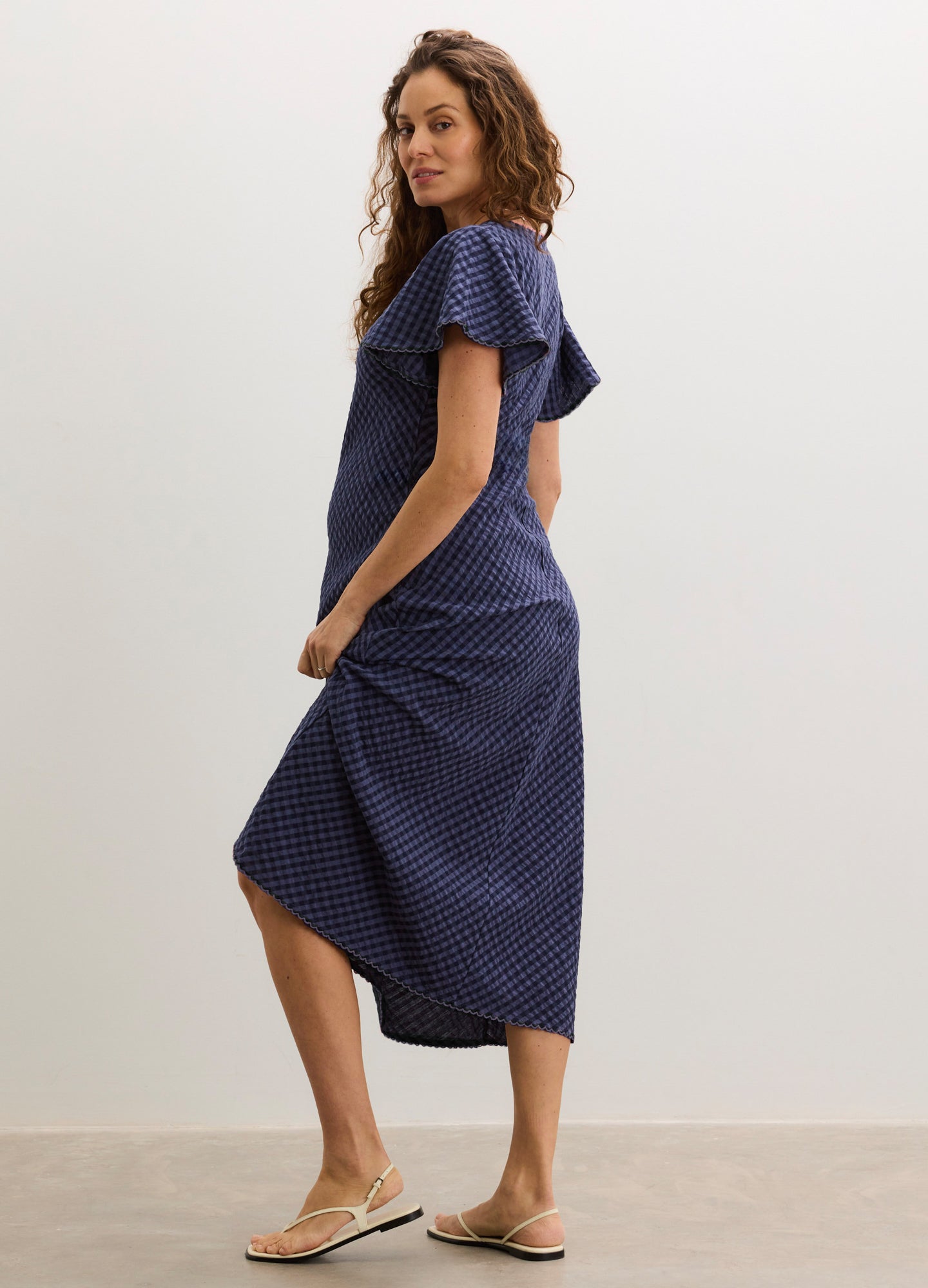 Navy blue maternity dress with white polka dots, flutter sleeves, and a midi length.
