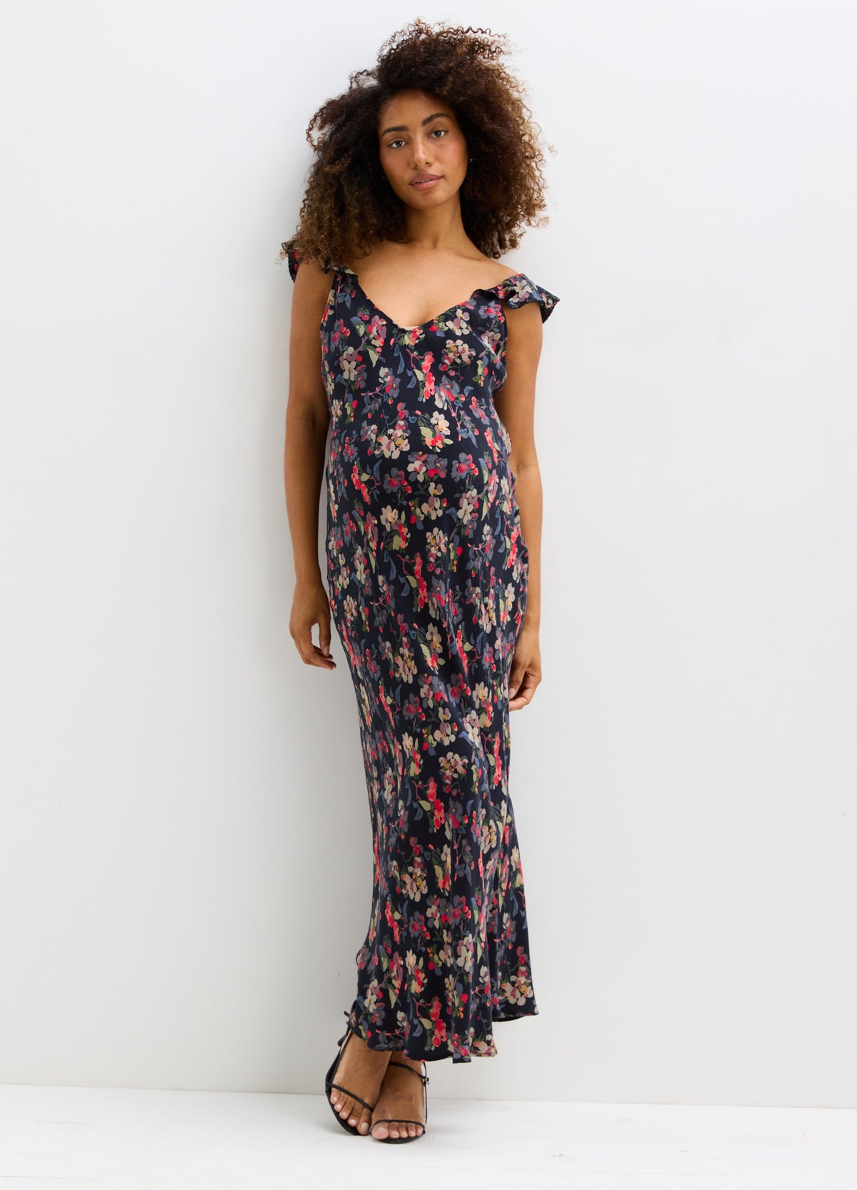 Navy blue maternity maxi dress with pink floral print, ruffled cap sleeves, and flowy skirt.