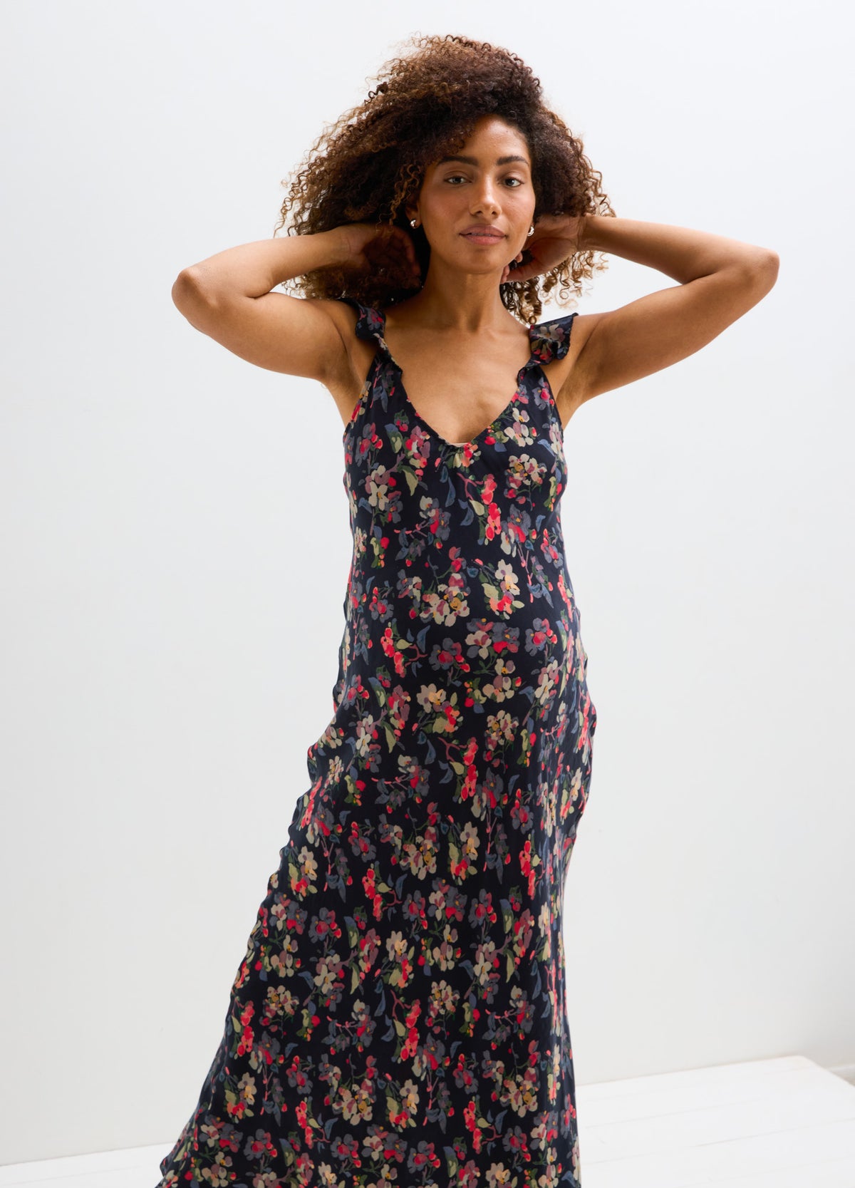 Black floral maternity dress with a fitted bust and flowing skirt designed for pregnant women.