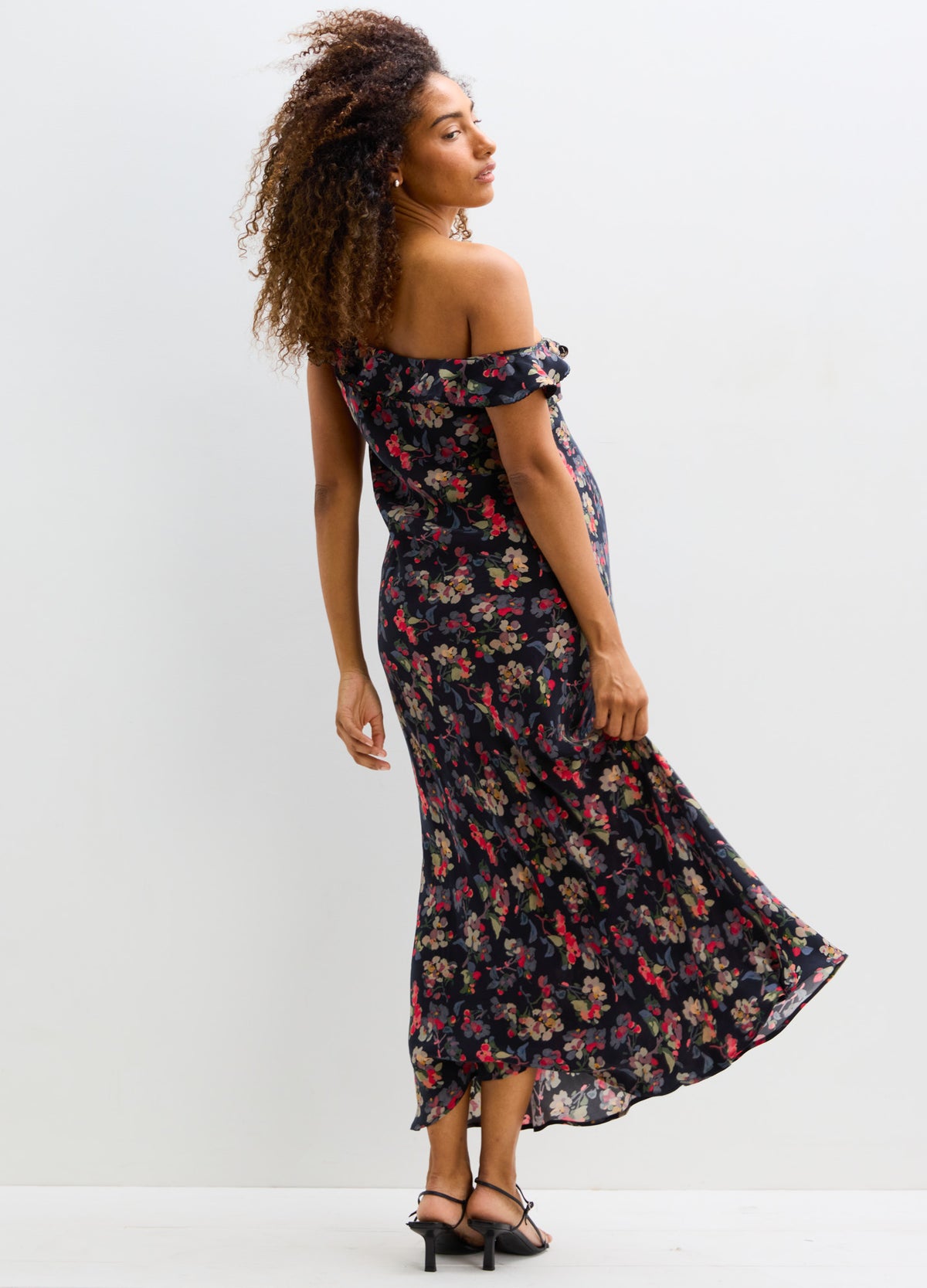 Black off-shoulder maternity dress with red and pink floral print, fitted bodice, and flowing skirt.