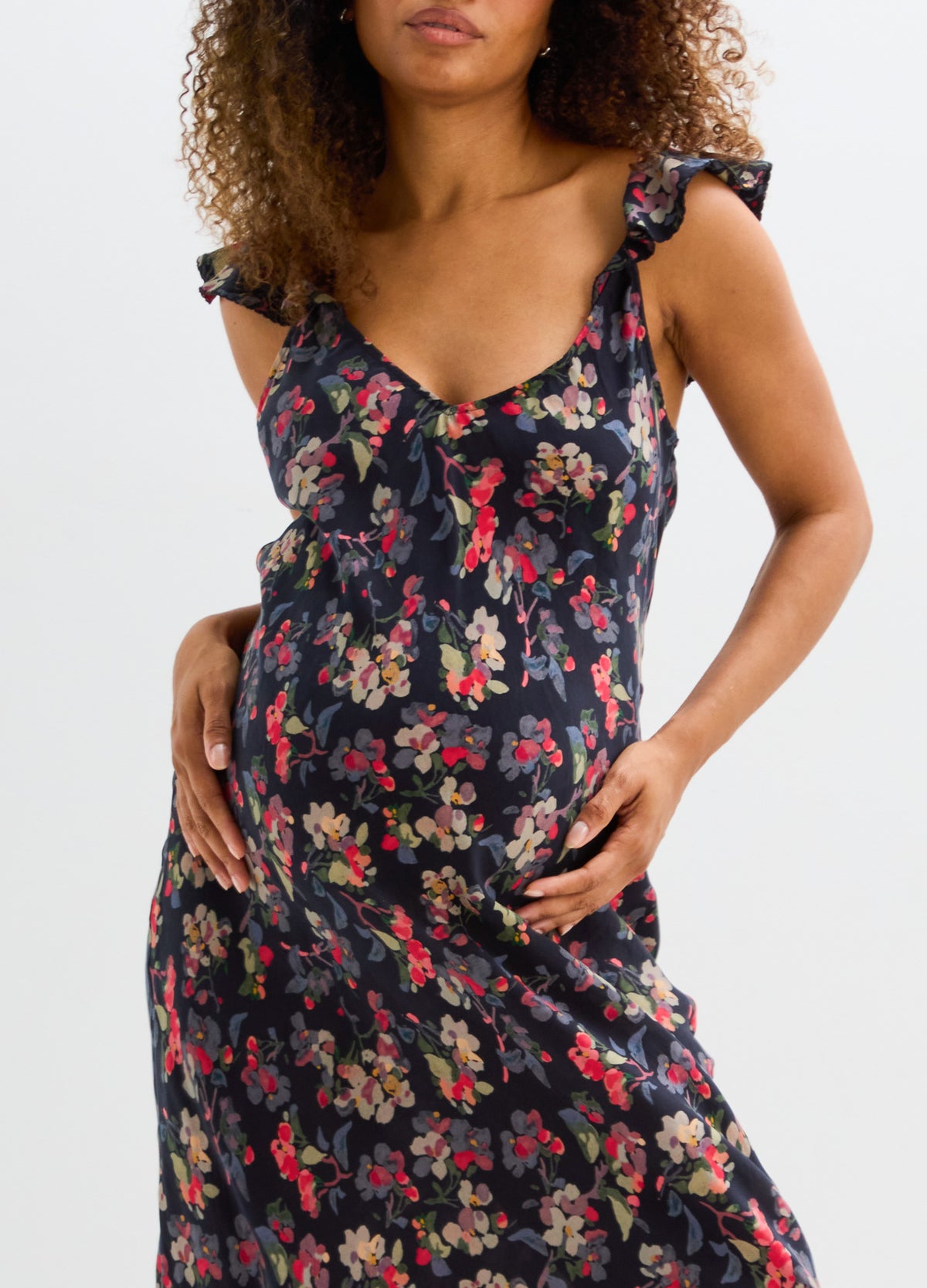 Black sleeveless maternity dress with red and pink floral print and ruffled shoulder straps.