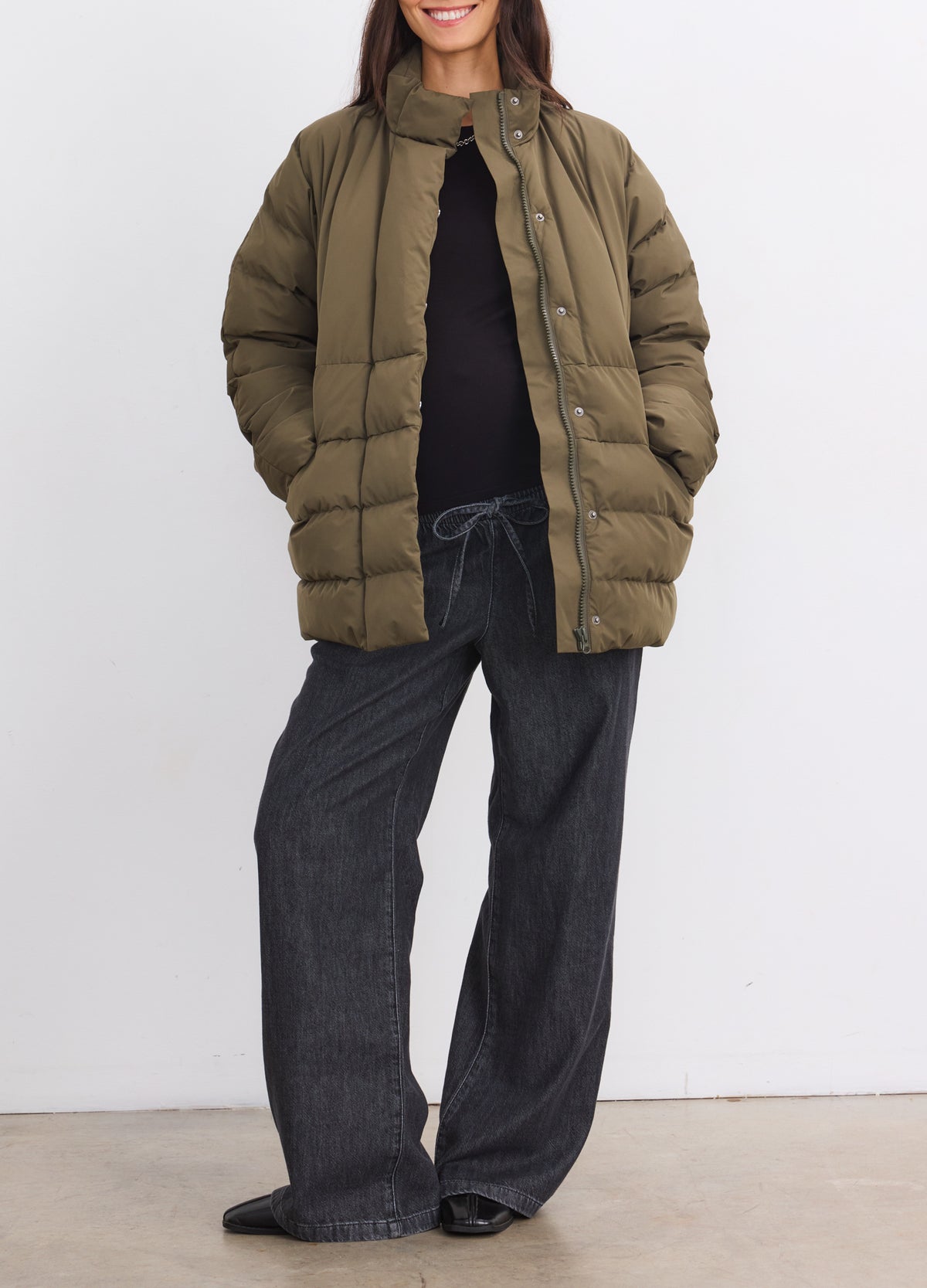 Olive green quilted maternity puffer jacket with stand collar and side pockets.