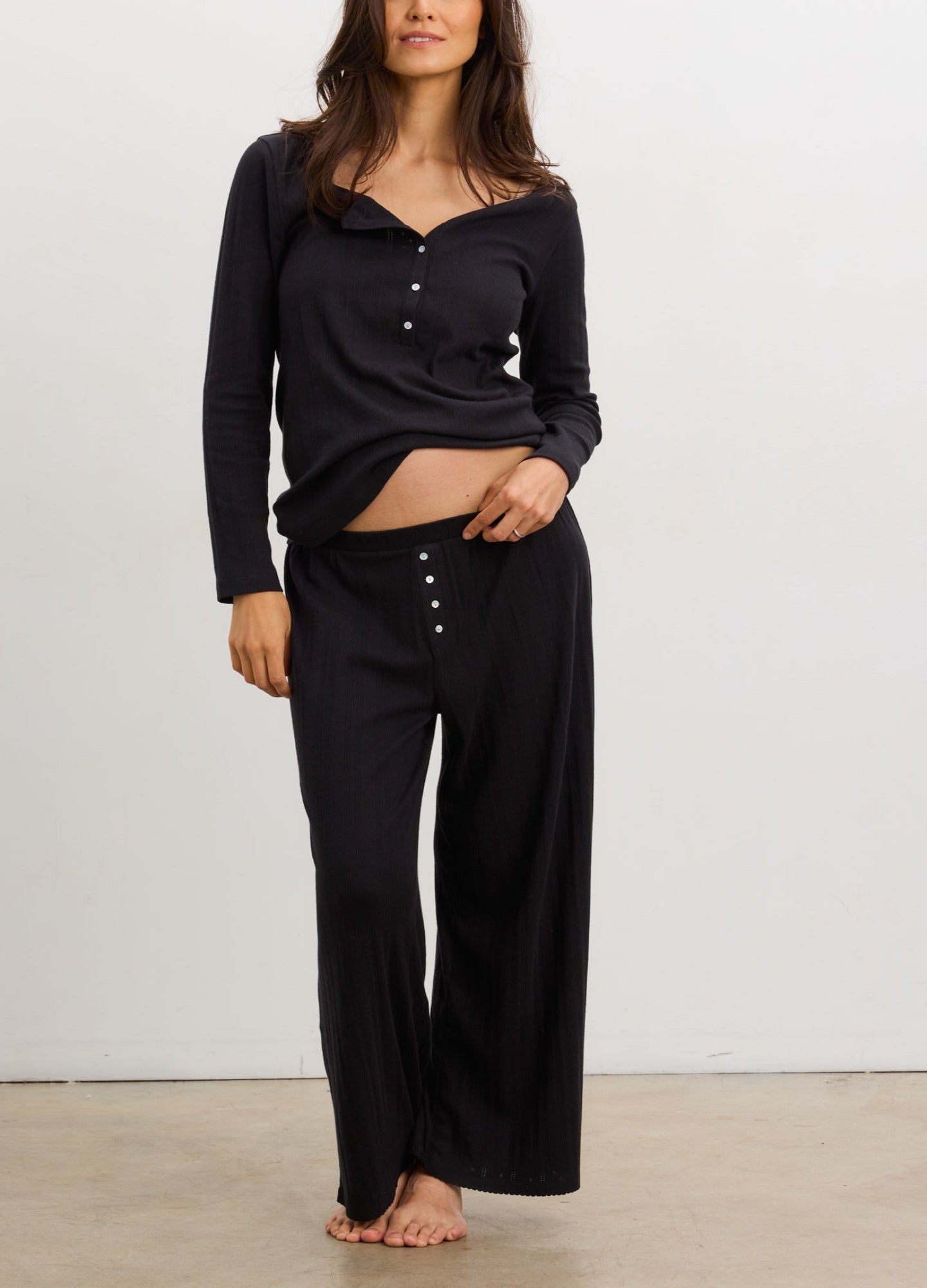 Black long sleeve maternity henley top with button detail paired with loose black maternity pants.