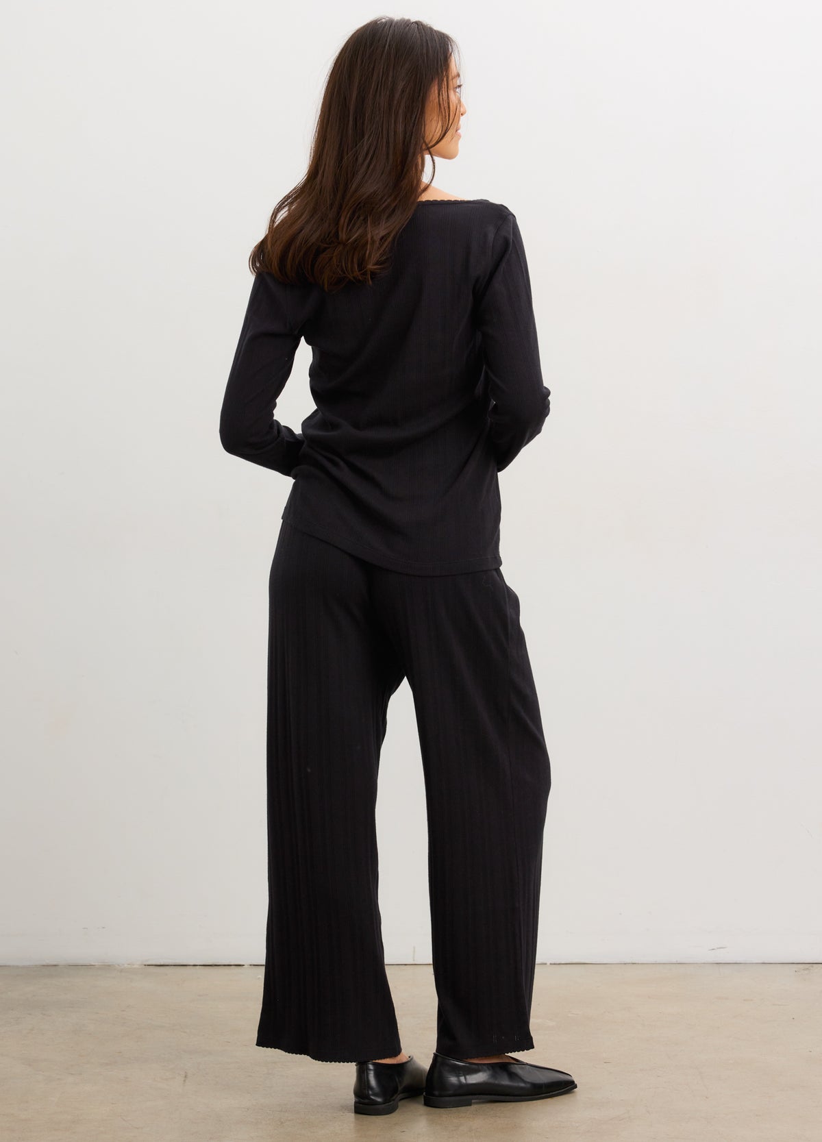 Black soft knit maternity lounge pants with wide legs and elastic waistband, modeled from the back.