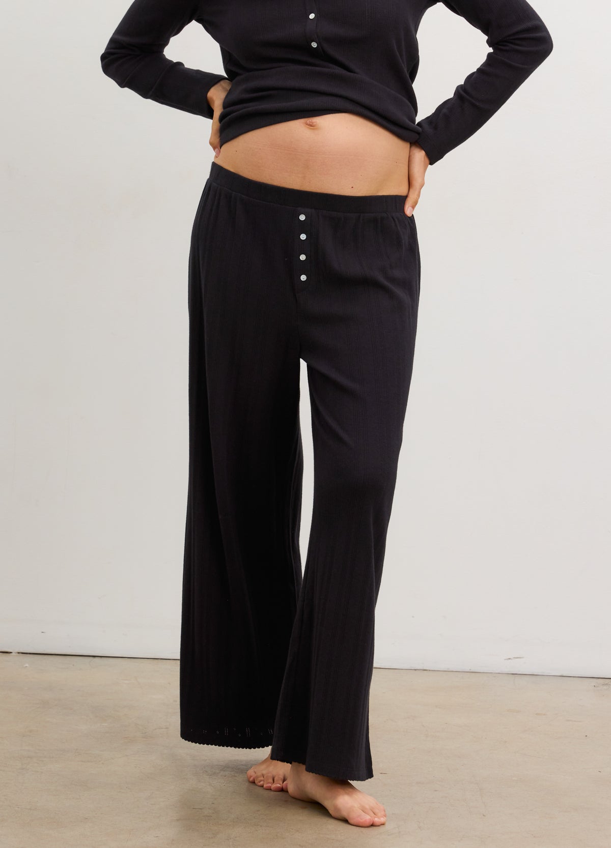 Black wide-leg maternity pants with buttoned waistband detail, soft stretchy fabric.