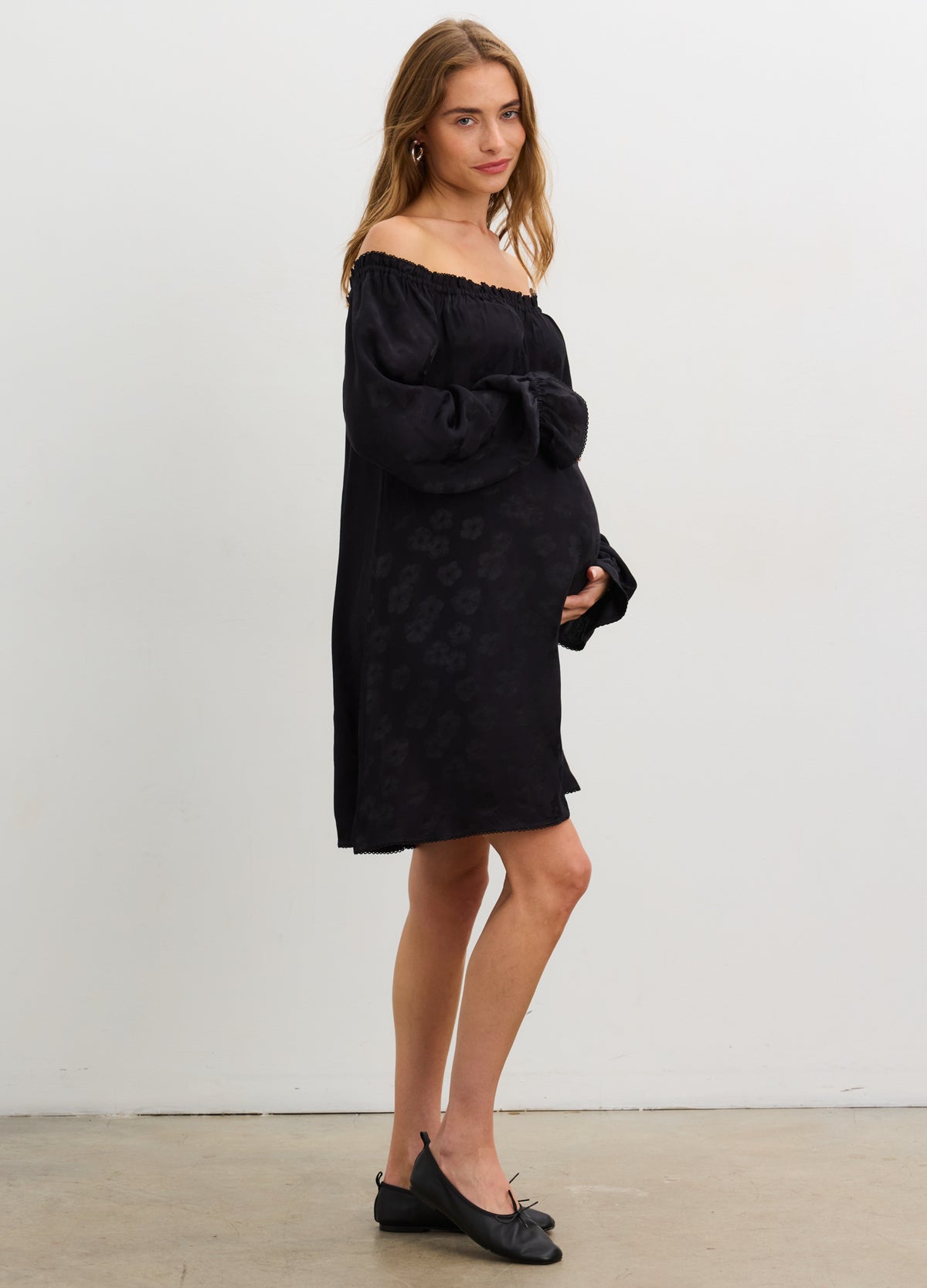 Black off-the-shoulder jacquard mini dress with maternity fit, worn by pregnant model.