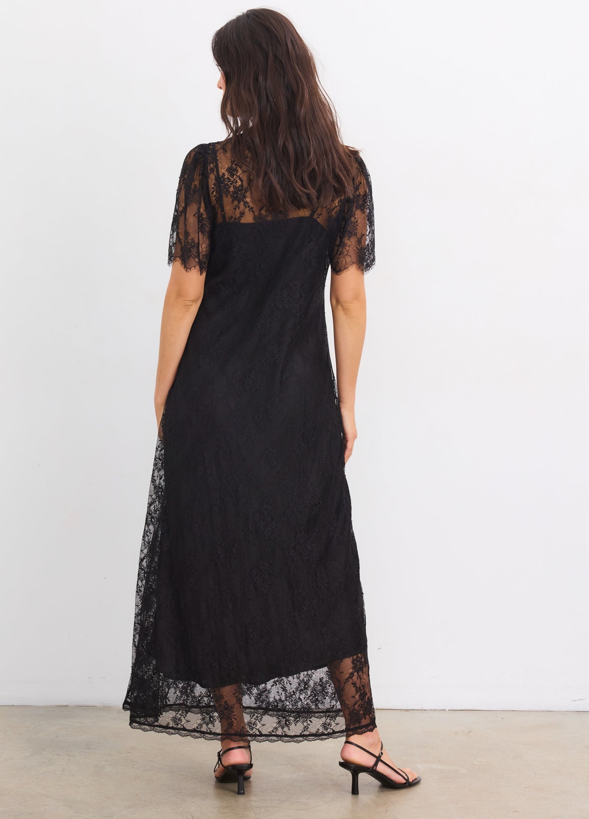 Black lace maternity dress with sheer short sleeves and a long, flowing silhouette.