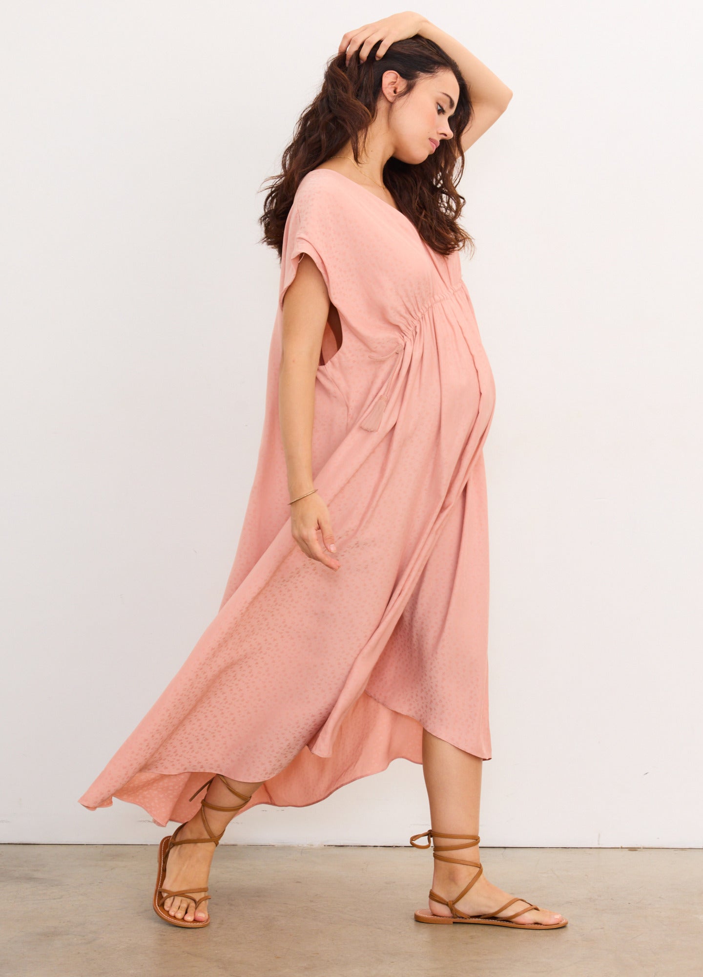 Soft pink maternity caftan with short sleeves and gathered waist detail, flowing ankle-length cut.