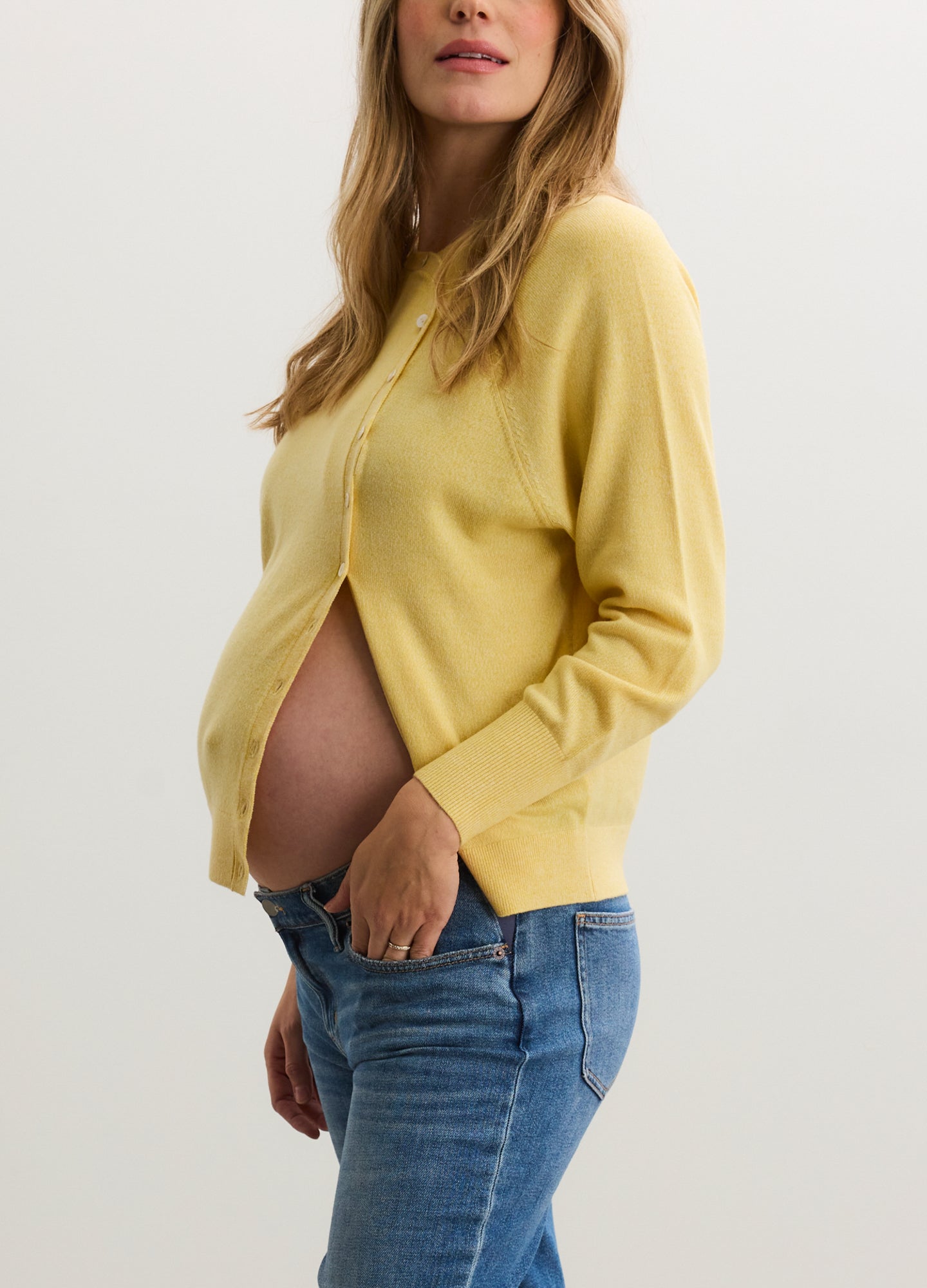 Soft yellow maternity cardigan with long sleeves and button-up front, worn open over baby bump.