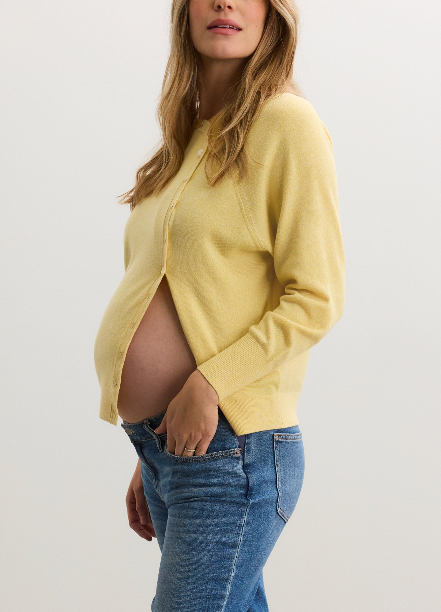 Soft yellow maternity cardigan with long sleeves and buttons, paired with blue jeans.