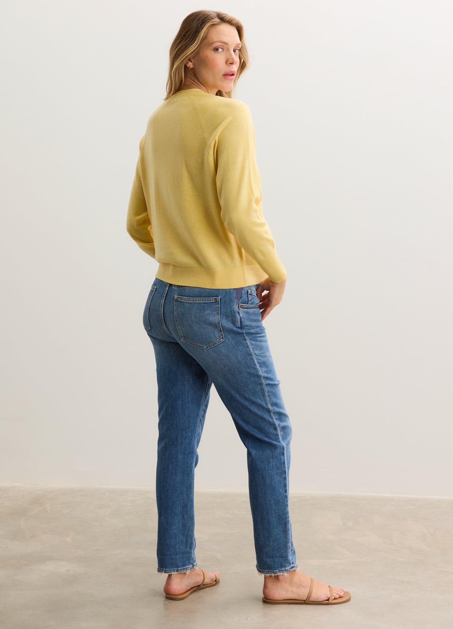 Soft yellow maternity cardigan with long sleeves and a relaxed fit, paired with blue jeans.