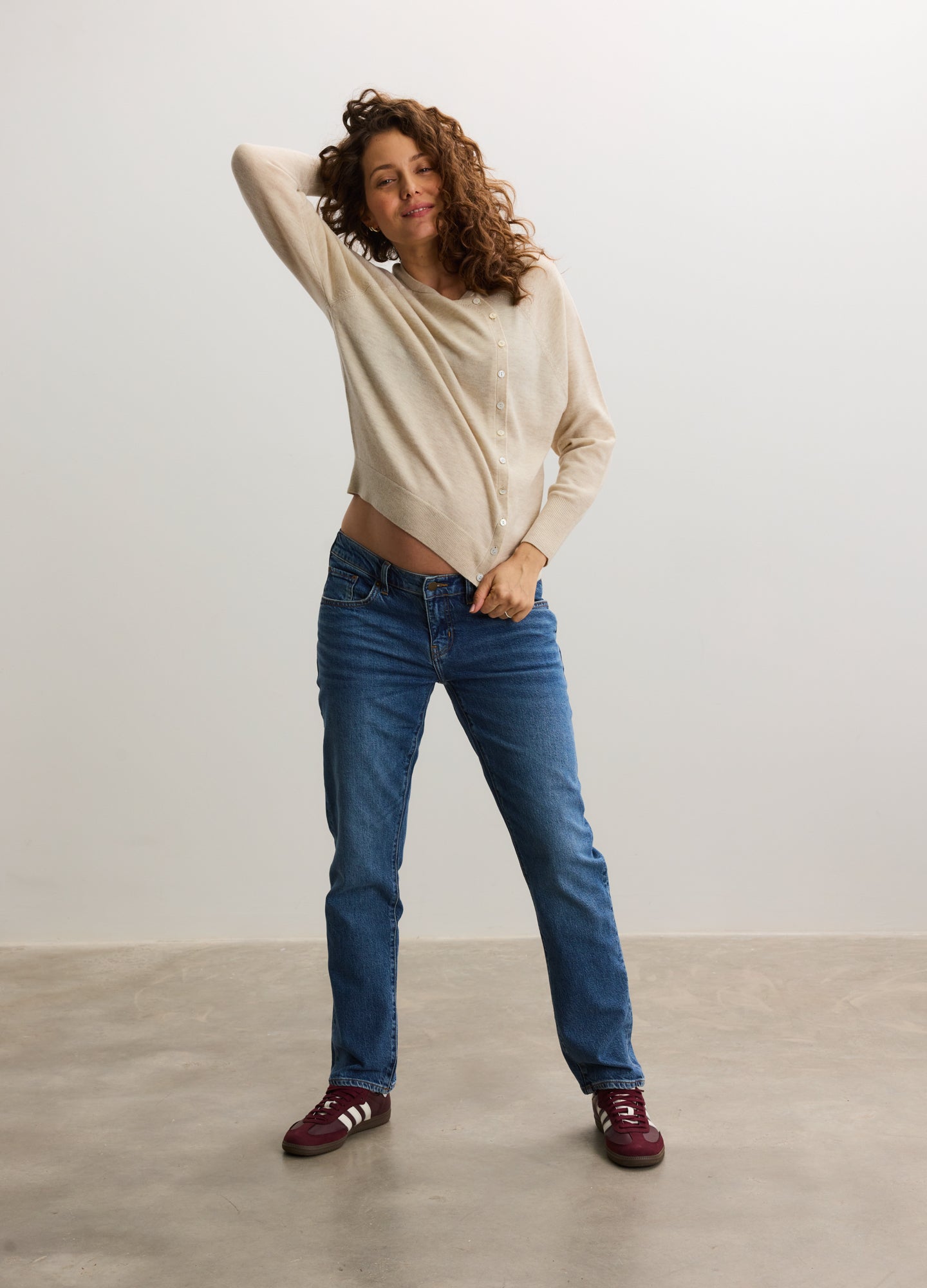 Beige maternity cardigan with long sleeves and relaxed fit, paired with dark blue jeans and burgundy shoes.