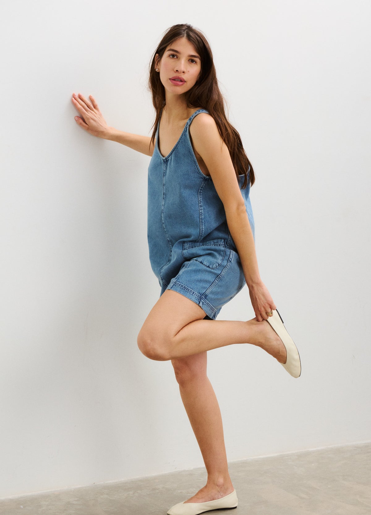 Blue denim sleeveless maternity romper with adjustable straps and relaxed shorts fit.