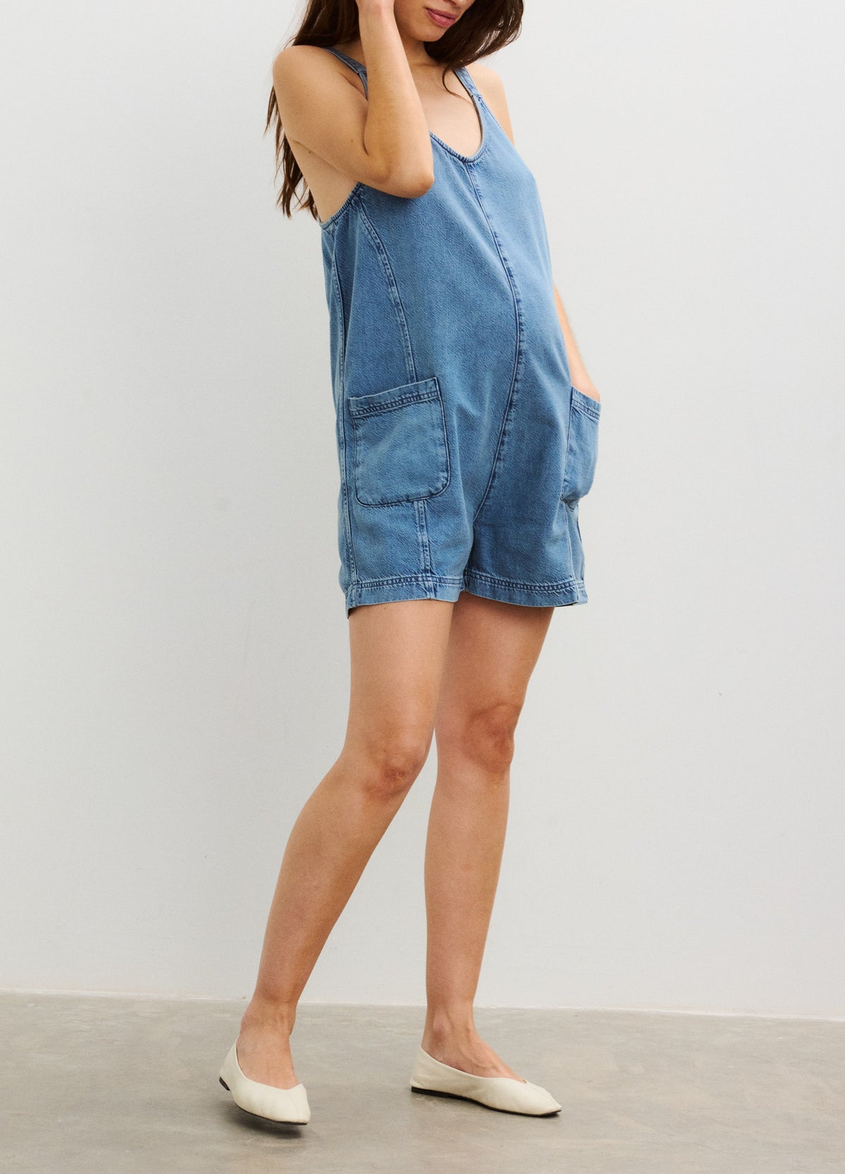 Light blue denim maternity romper with adjustable straps and front patch pockets, designed for pregnant women.