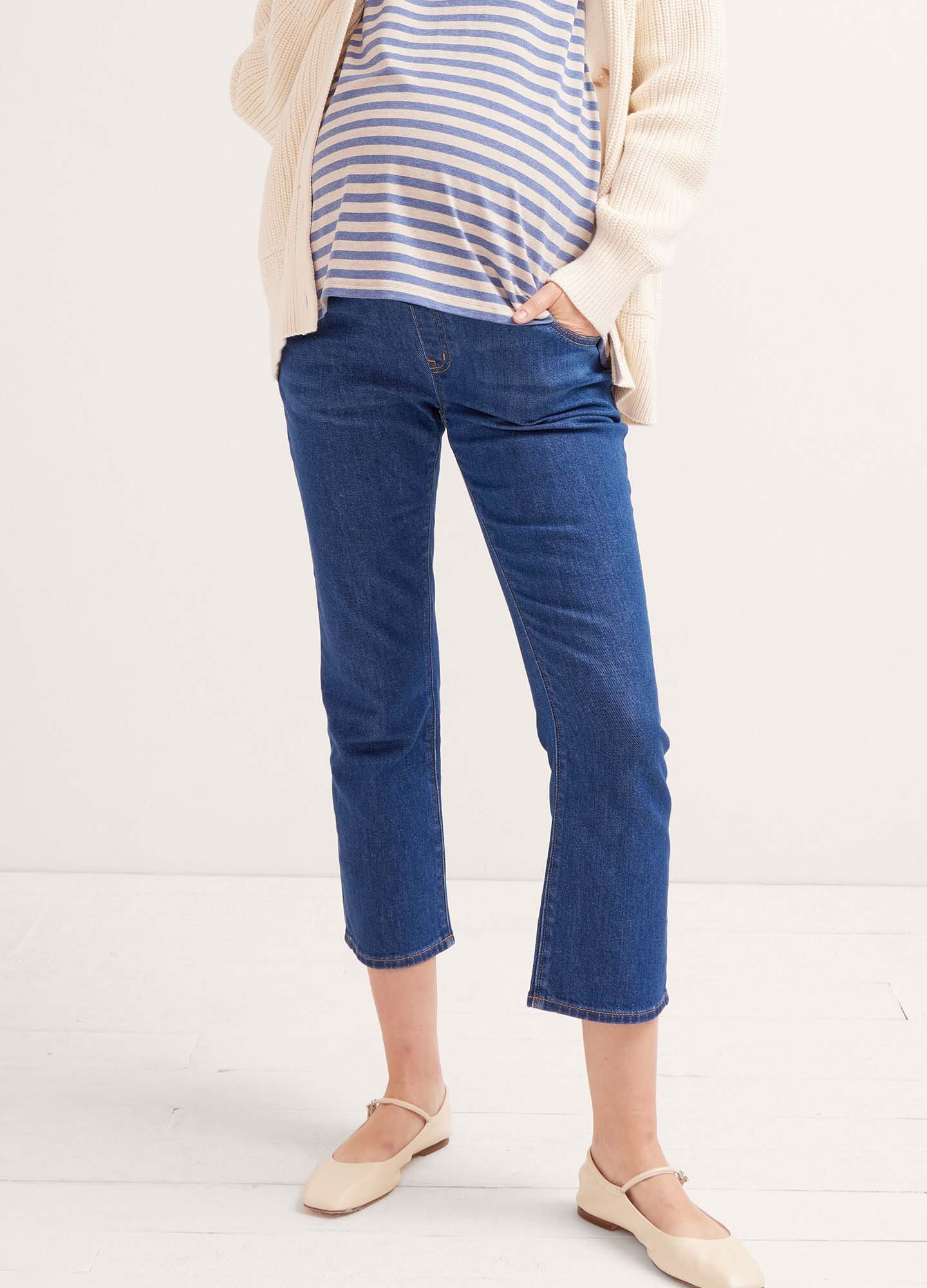 True blue cropped maternity jeans with over-the-bump design, worn by pregnant model.