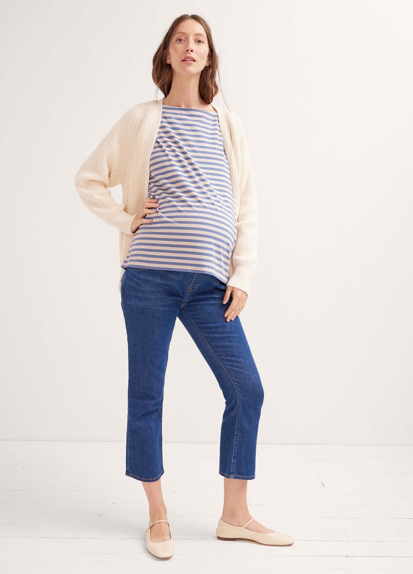 Pregnant woman wearing true blue maternity over the bump crop jeans with a striped top and light cardigan.