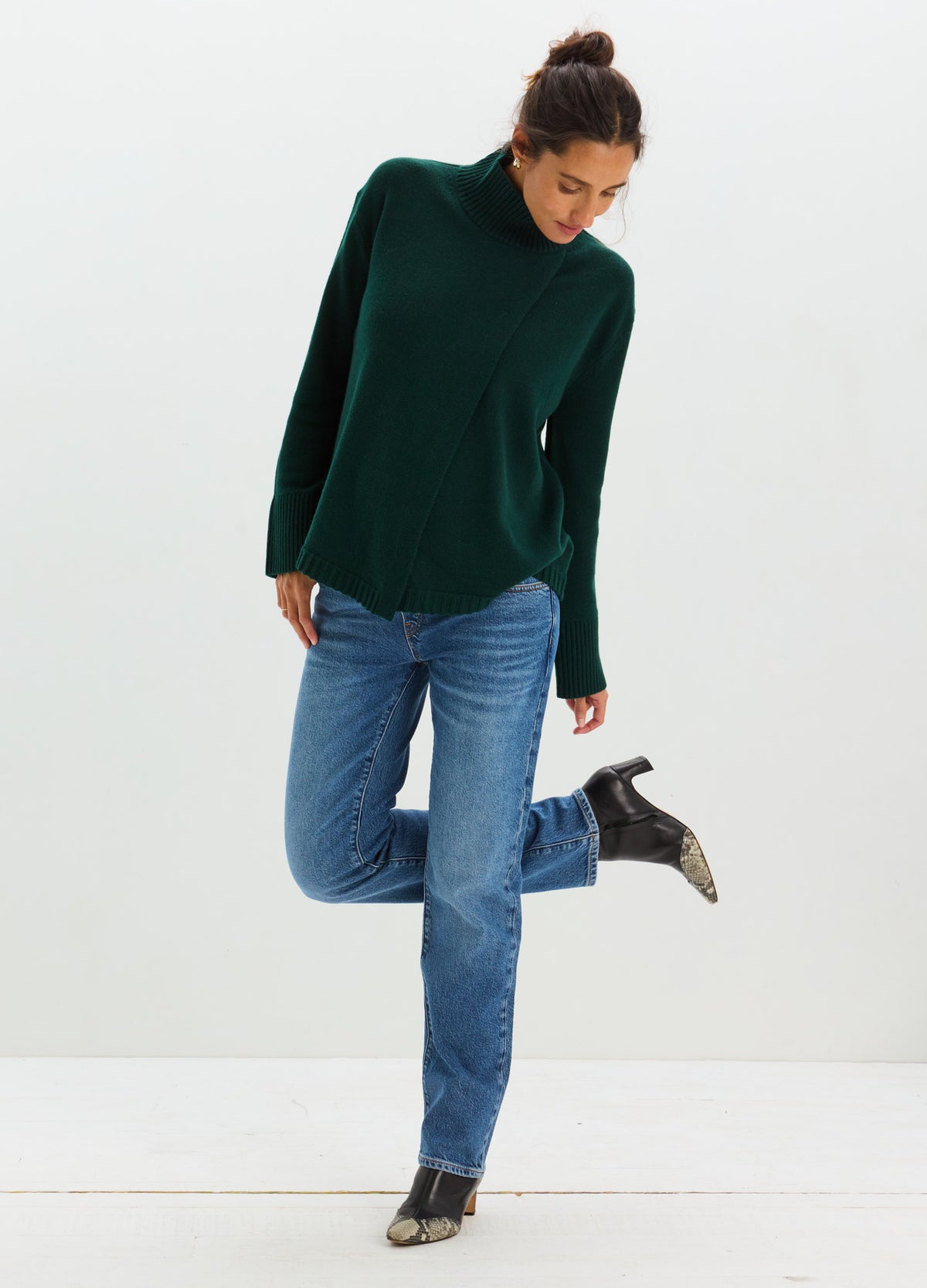 Blue straight-leg maternity jeans with an over-the-bump stretchy panel, worn with a dark green turtleneck sweater and black.
