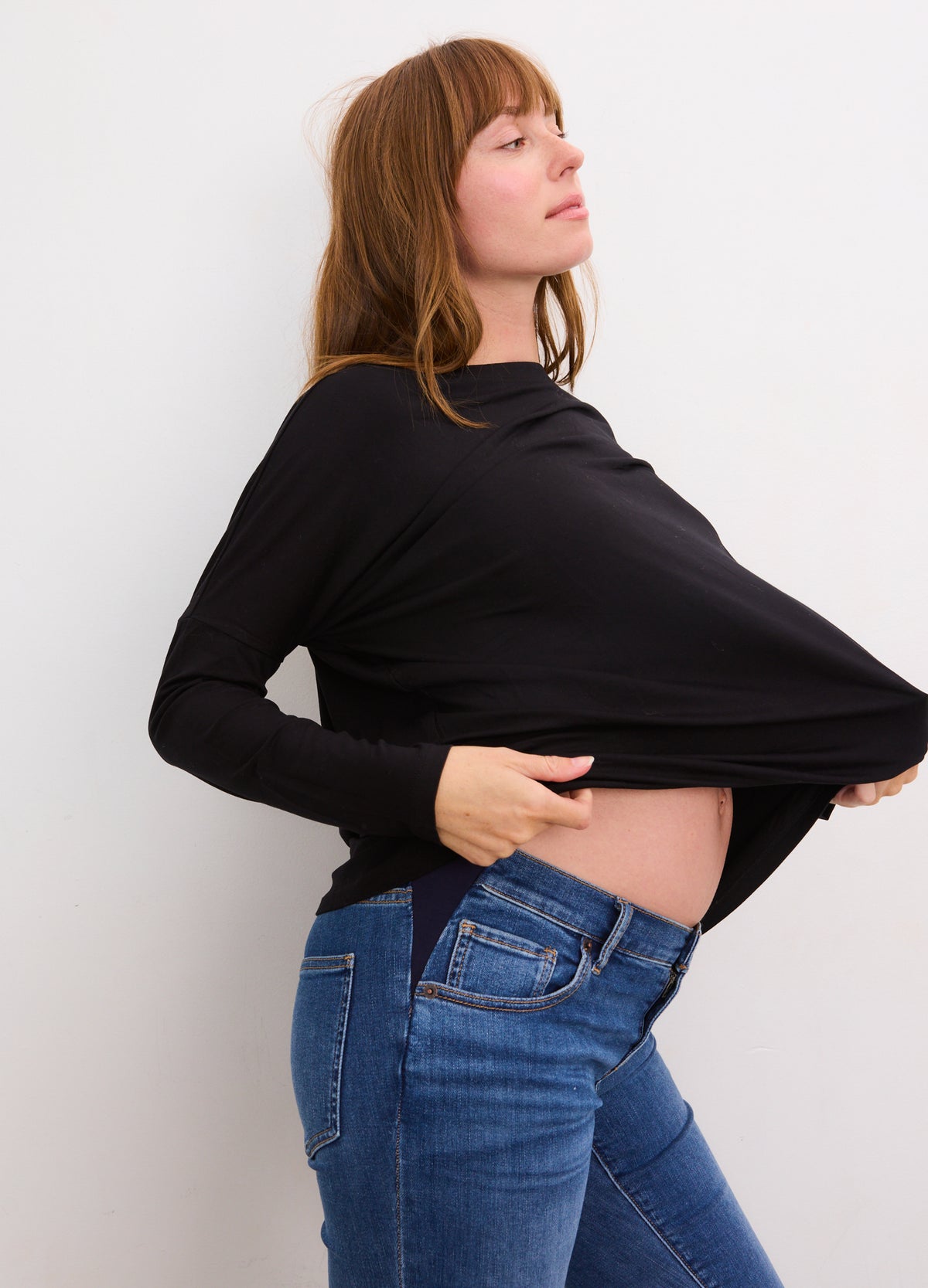 Black long-sleeve maternity tee worn by pregnant woman, stretchy fabric with fitted silhouette.