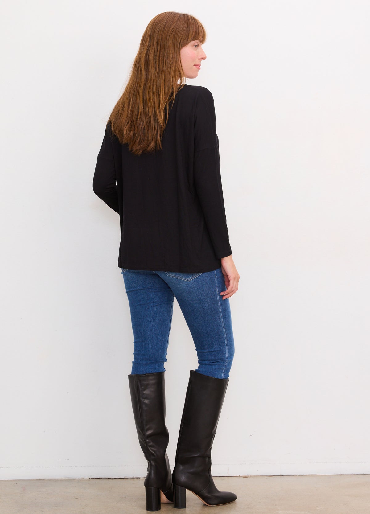 Black long-sleeve maternity tee with a relaxed fit, paired with blue jeans and black knee-high boots.