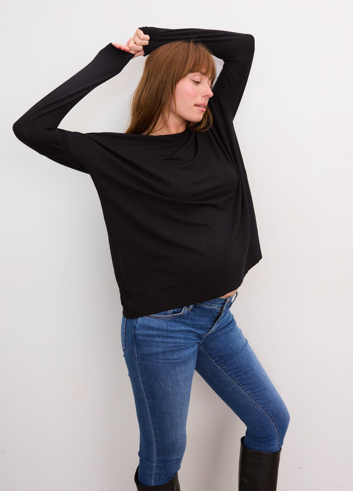 Black long-sleeve maternity tee with relaxed fit worn with blue jeans.