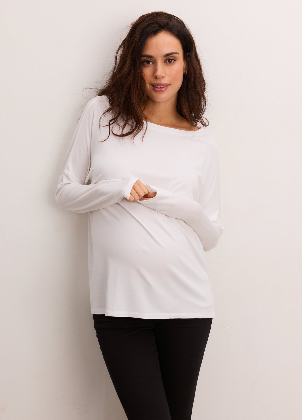 Pregnant woman wearing white maternity longsleeve tee with stretchy, soft fabric and scoop neckline.