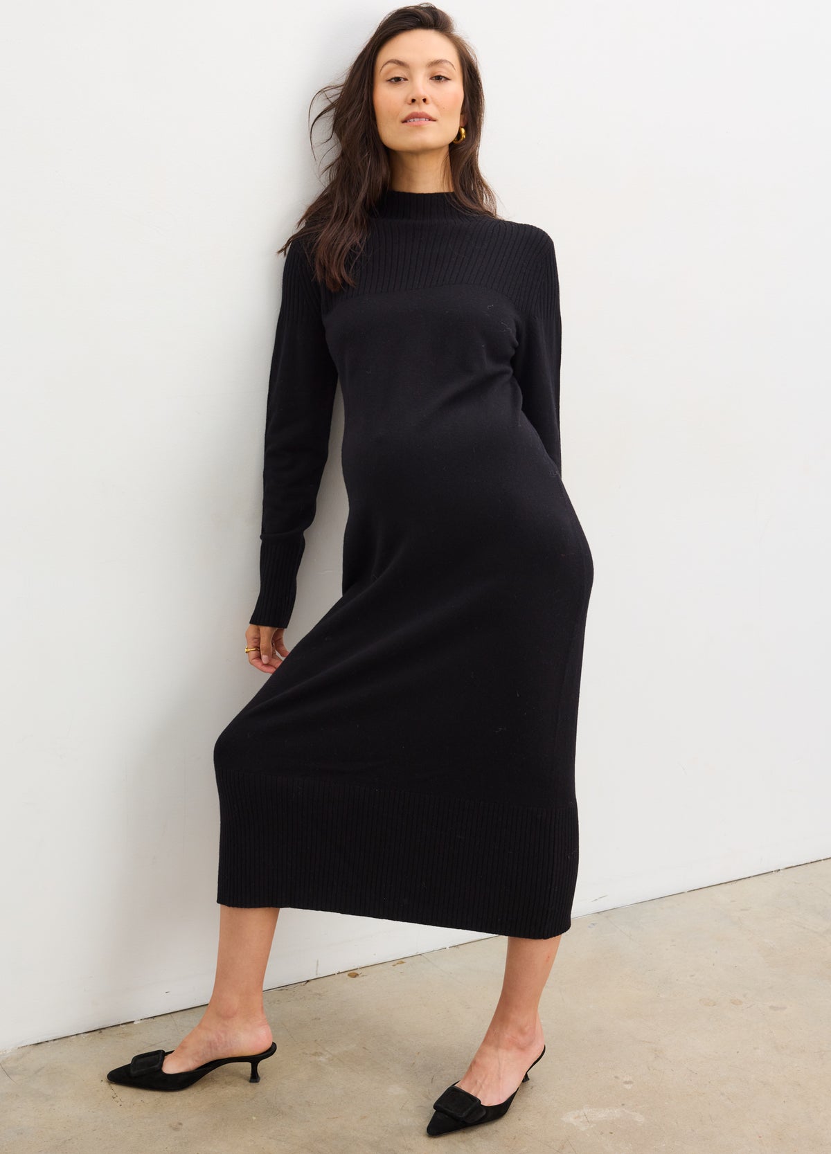 Black maternity mockneck sweater dress with long sleeves, fitted to pregnant figure, midi length.