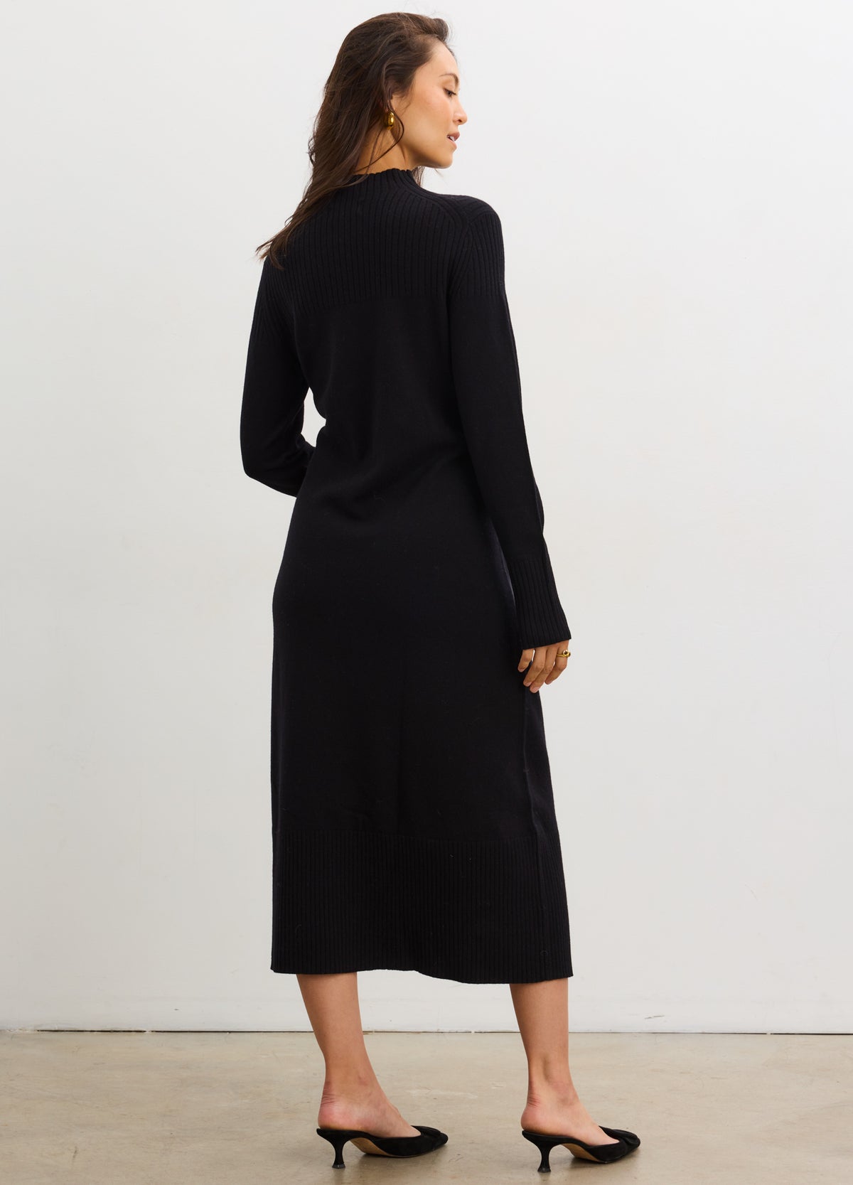 Black knitted mockneck sweater dress with long sleeves, mid-calf length, designed for maternity fit.