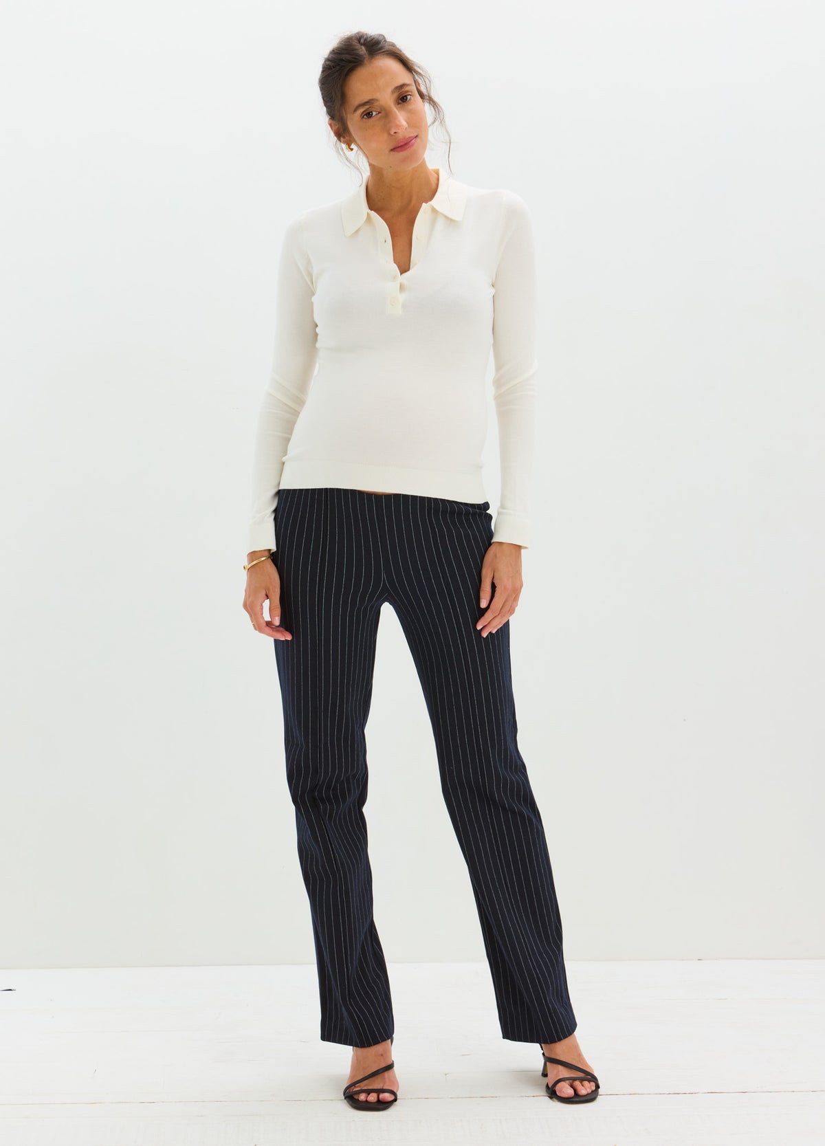 Black pinstripe maternity work pants with contoured seaming and stretch fabric modeled by a pregnant woman.