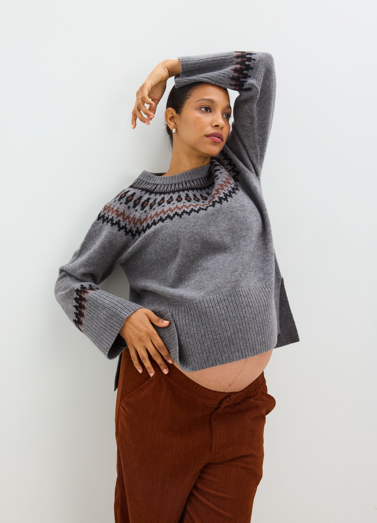 Charcoal gray knit sweater with a wide boat neckline, relaxed sleeves, and a patterned fair isle yoke in black, rust, and.