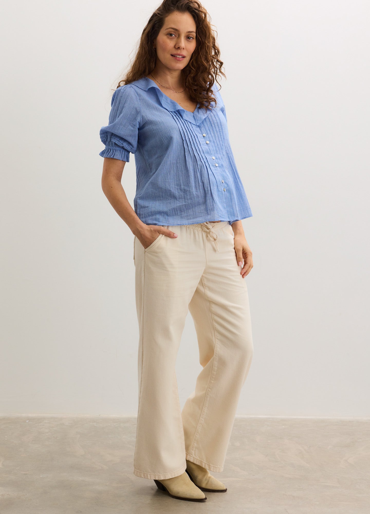 Light blue maternity nursing blouse with button front and quarter sleeves paired with cream wide-leg pants and beige ankle.