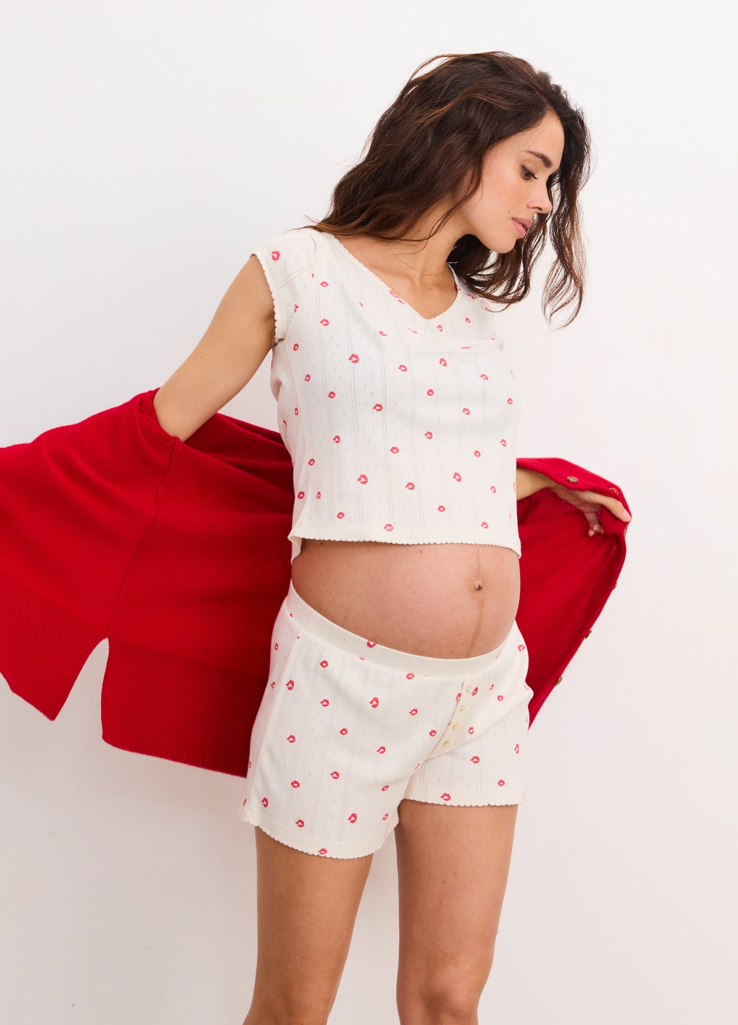White maternity boxer shorts with small red floral pattern worn by pregnant woman, paired with matching sleeveless crop top.