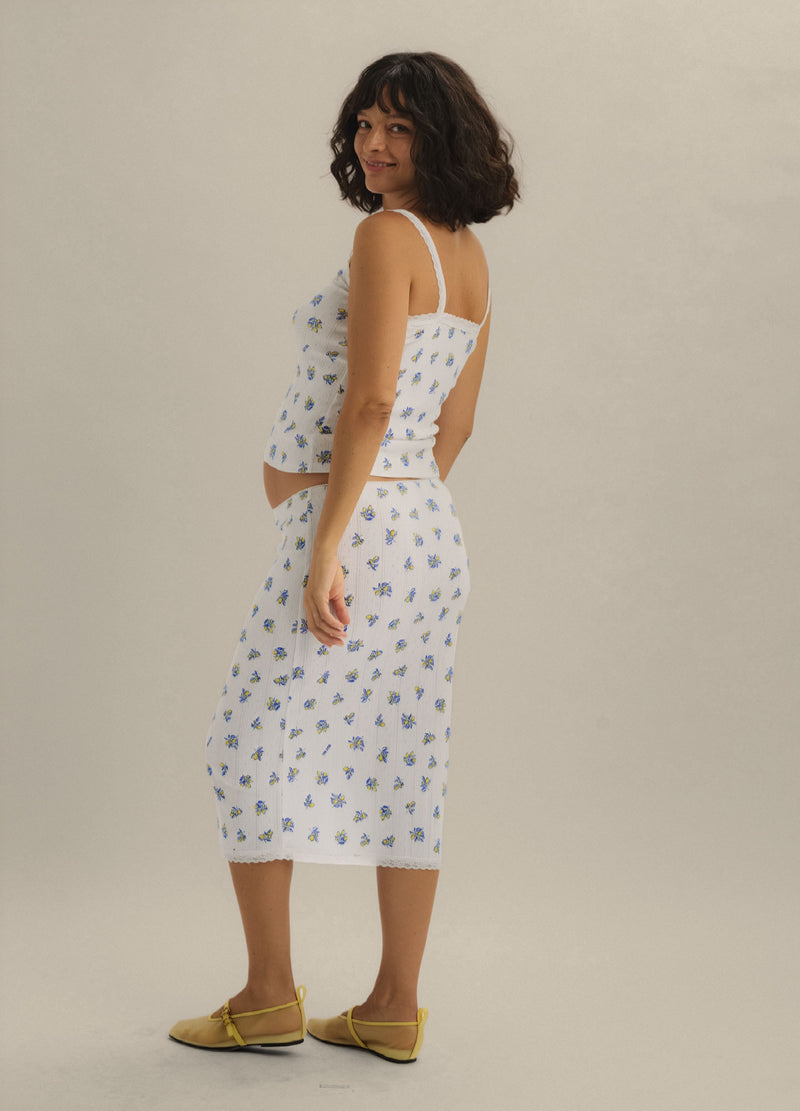 White midi maternity skirt with delicate blue floral pointelle knit, fitted silhouette.