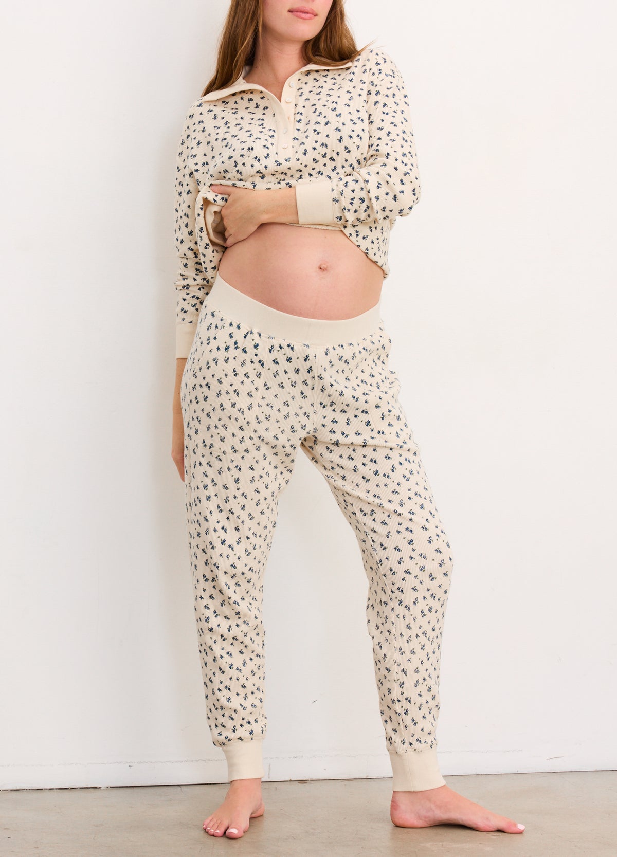 Cream waffle-knit maternity joggers with small black floral print and a wide elastic waistband designed for pregnancy.