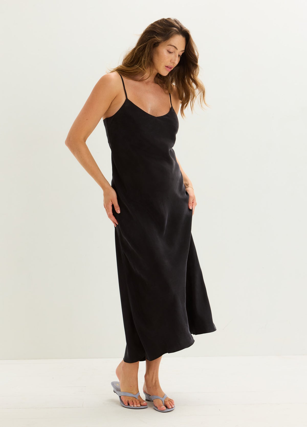 Black satin maternity slip dress with spaghetti straps and a flowing skirt.