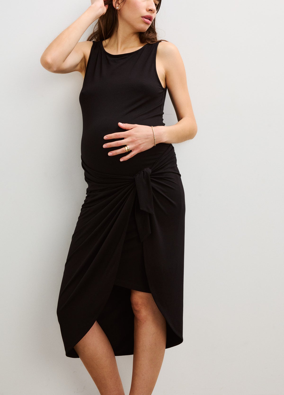 Black sleeveless maternity wrap dress with ruched side and asymmetrical midi hem.