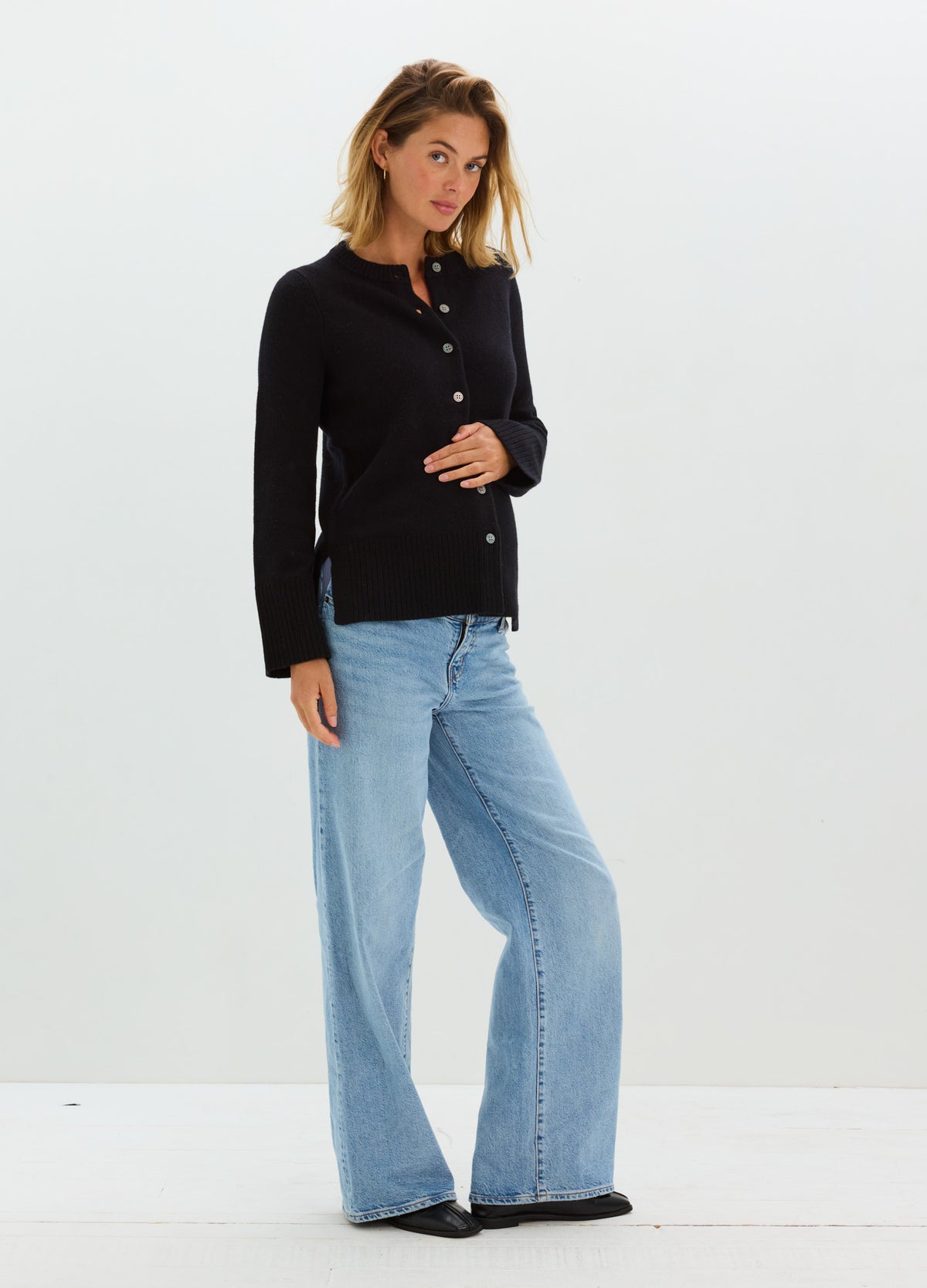 Pregnant model wearing light-wash blue wide-leg maternity jeans with a relaxed fit.