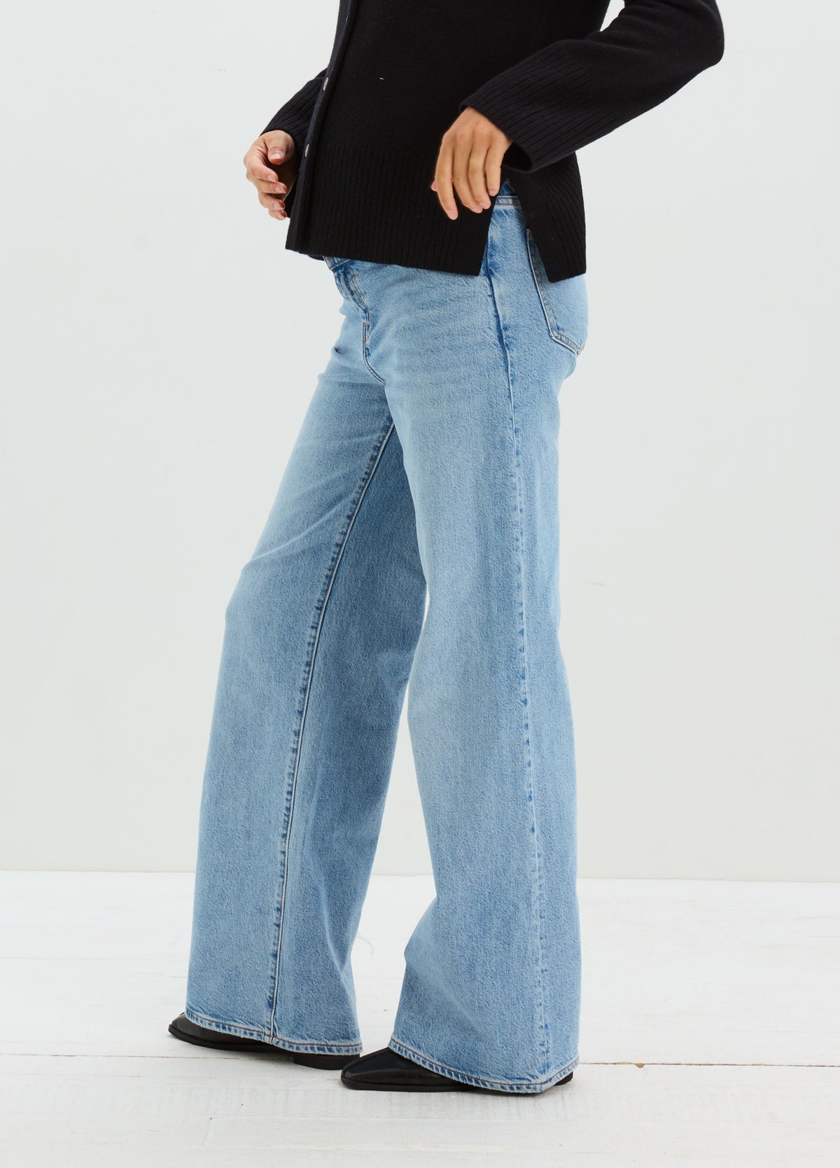 Pregnant model wearing light blue maternity jeans with a relaxed wide-leg fit and faded denim wash.