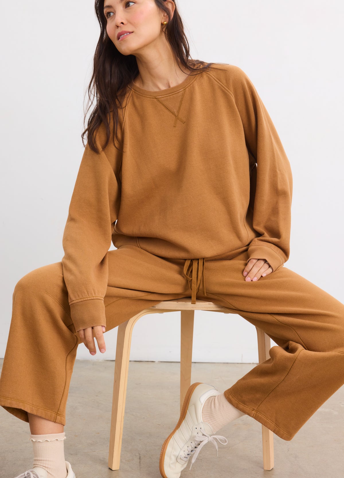 Pregnant woman wearing rubber-colored maternity Romy darted sweatpants with wide legs and matching relaxed sweatshirt.