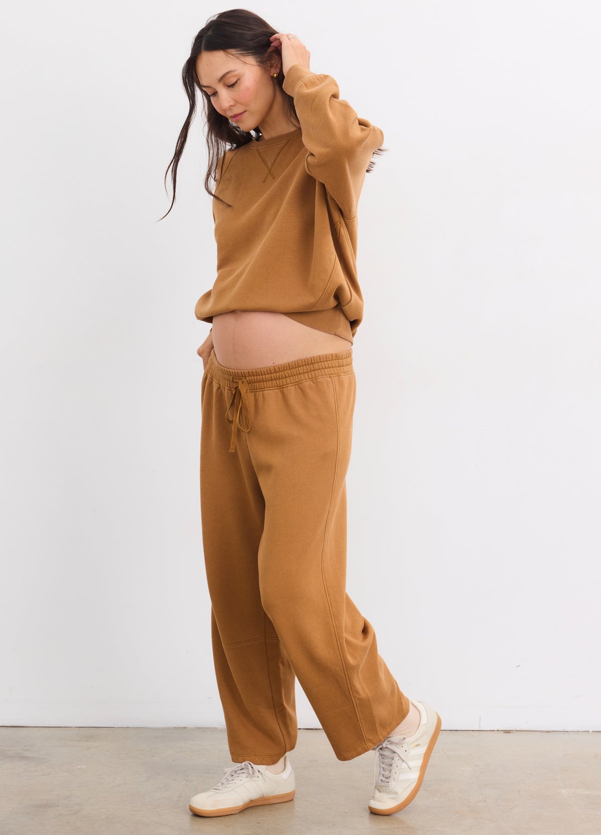 Pregnant woman wearing maternity Romy darted sweatpants in rubber color with a matching sweatshirt and white sneakers.