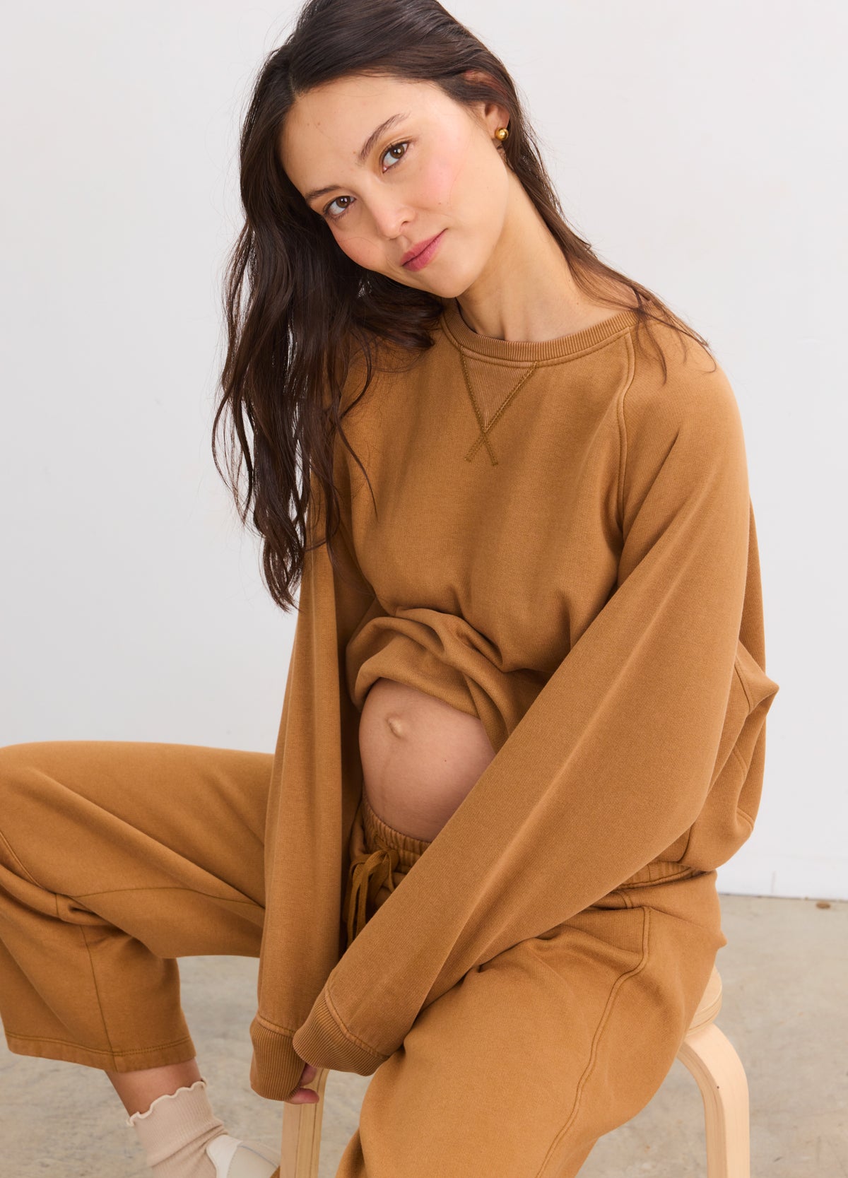 Pregnant woman wearing rubber-colored maternity sweatshirt and matching sweatpants with relaxed fit and soft fabric.