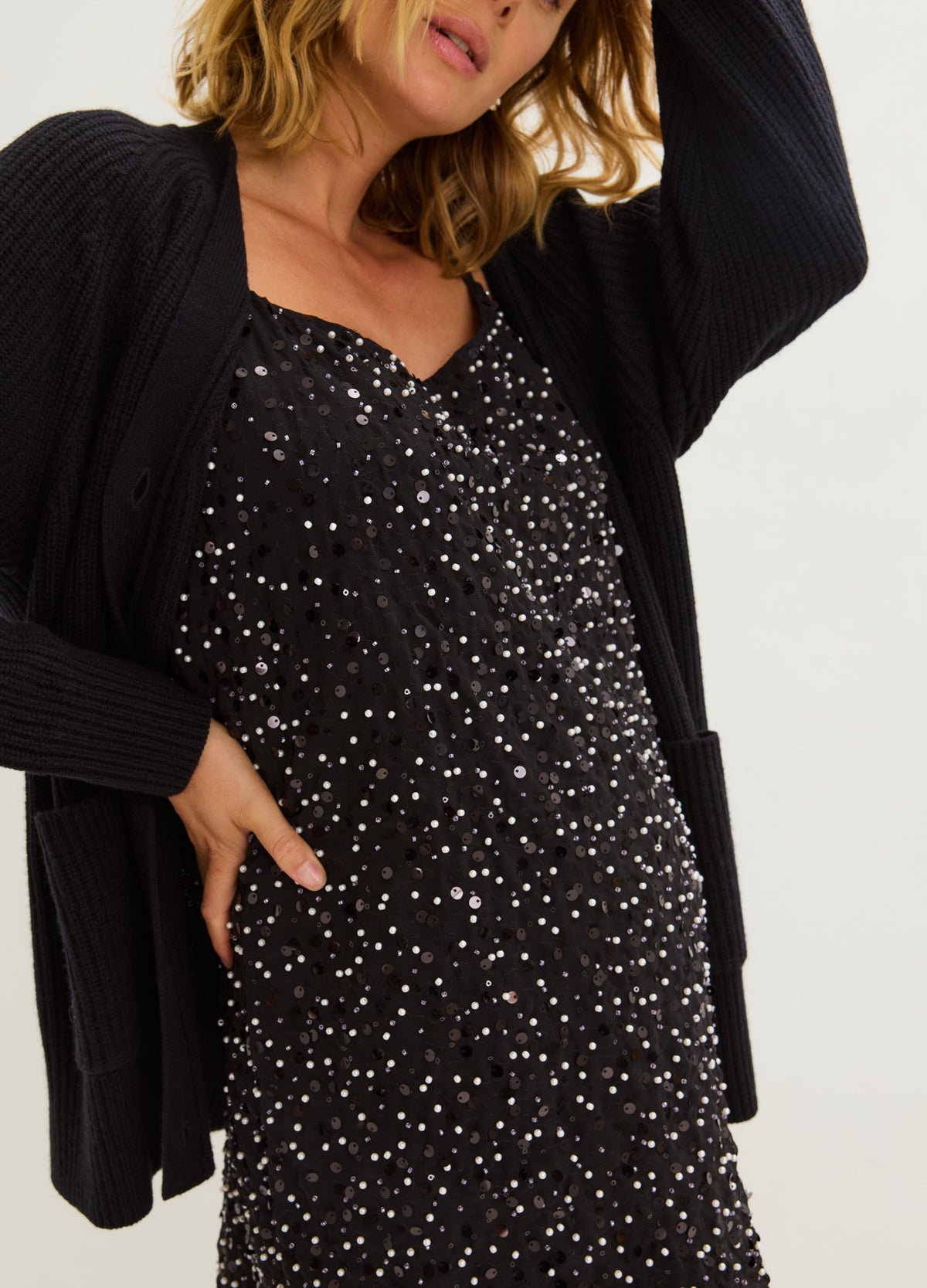 Black maternity mini dress with a relaxed fit and scattered silver sparkle, layered under a black cardigan.