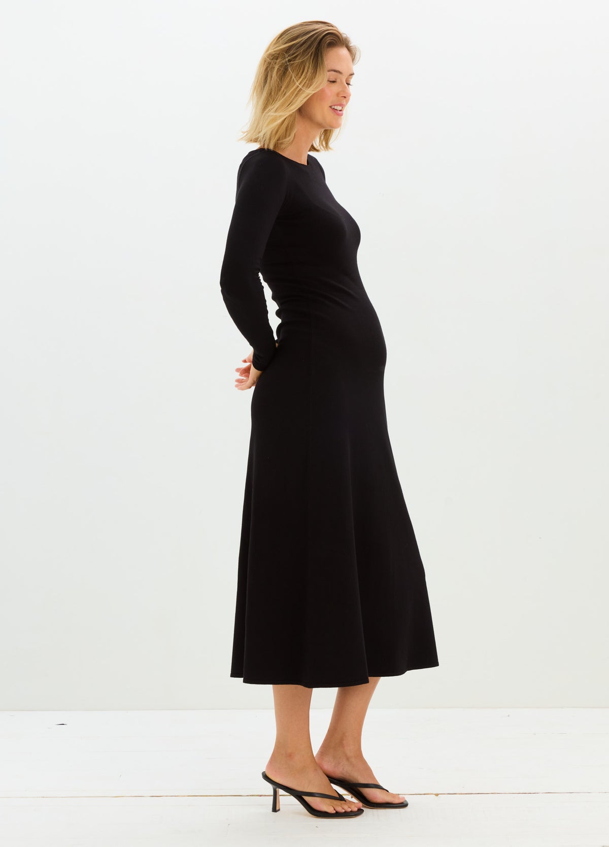 Black long-sleeve knit maternity dress with fitted bodice and flared midi skirt.